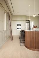 KJØKKEN: Også på kjøkkenet er det valgt det samme gulvet. Kjøkkenøyen er laget av en møbelsnekker og er valgt i en mørk farge som kontrast til alt det lyse. Den buede formen fungerer også som kontrast til alle kantene som ellers er på kjøkkenet.