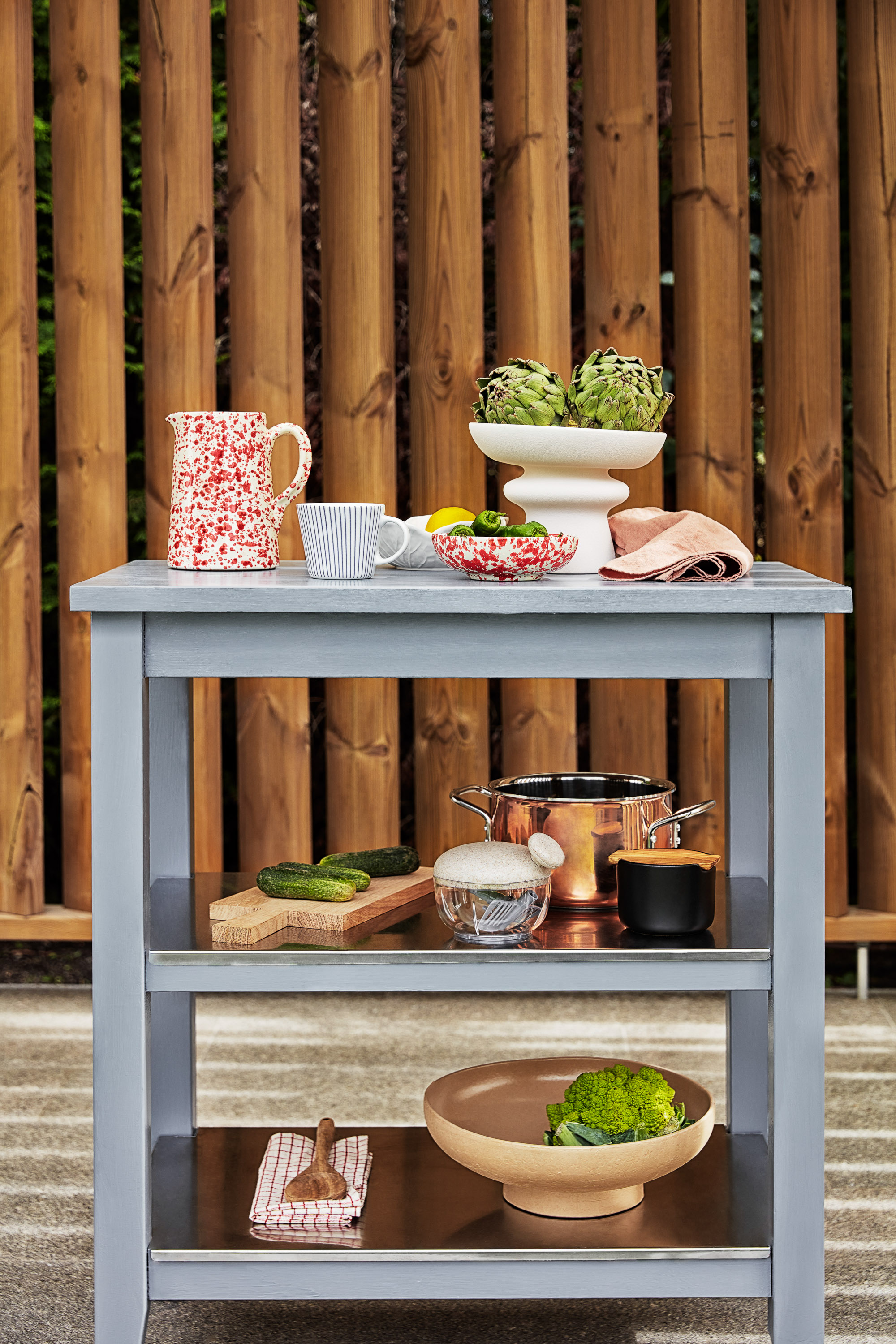 blått avlastningsbord på terrasse med brun trevegg bak