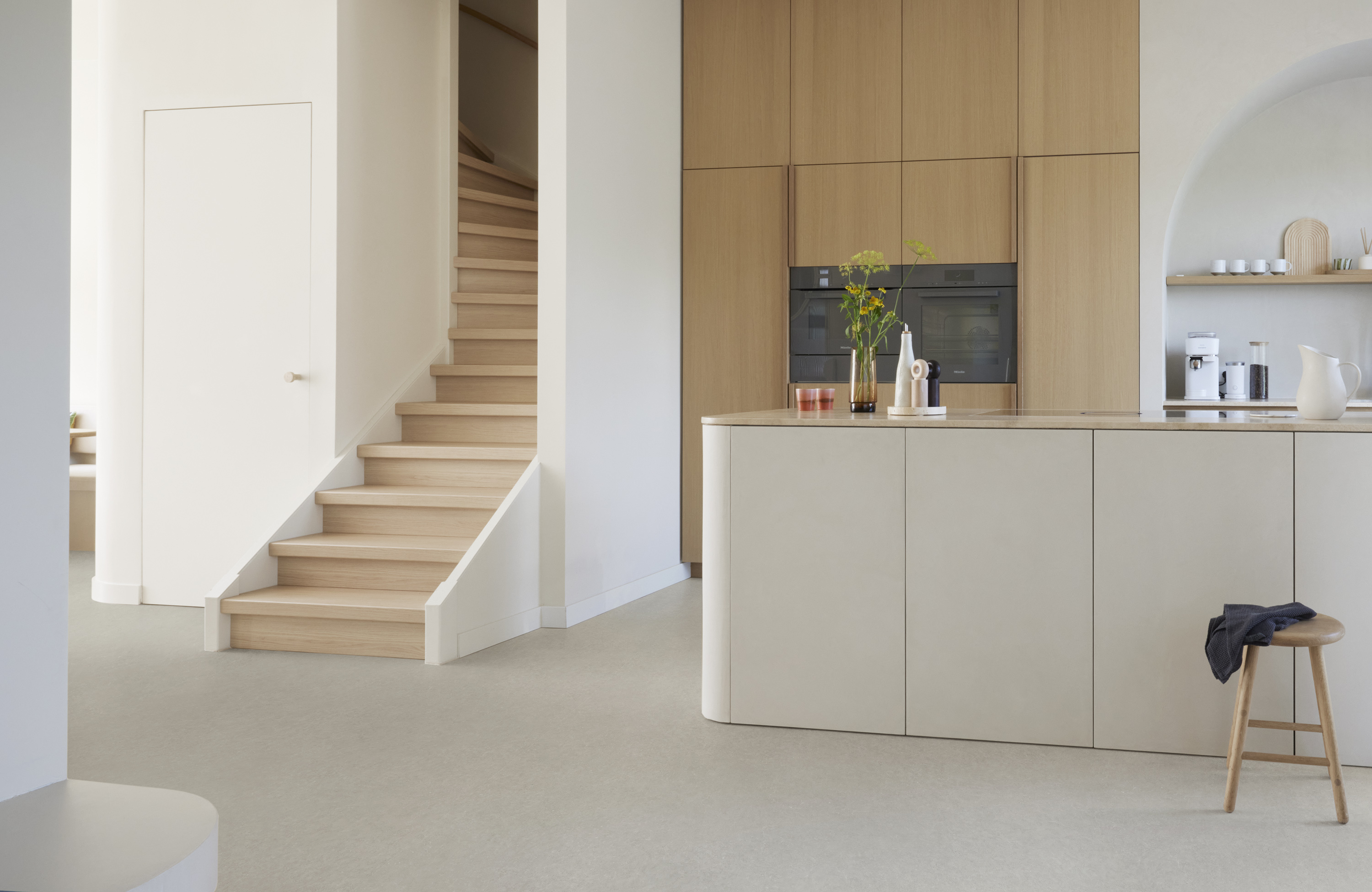 kjøkken med beige skap og beige gulv, trapp opp i hvitt og lyst tre