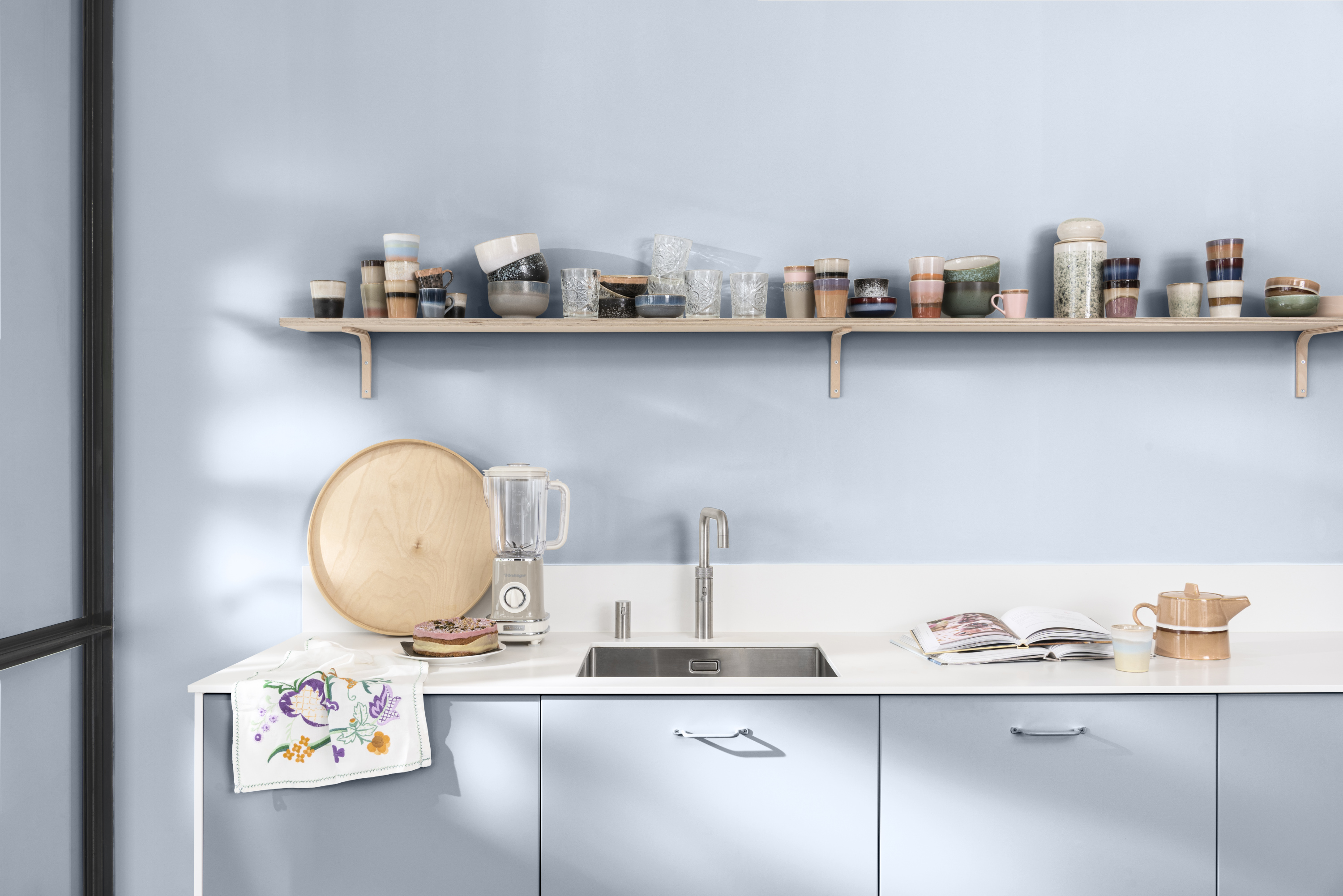 kjøkkenvegg med benkeskap malt i en lyst blå farge. 