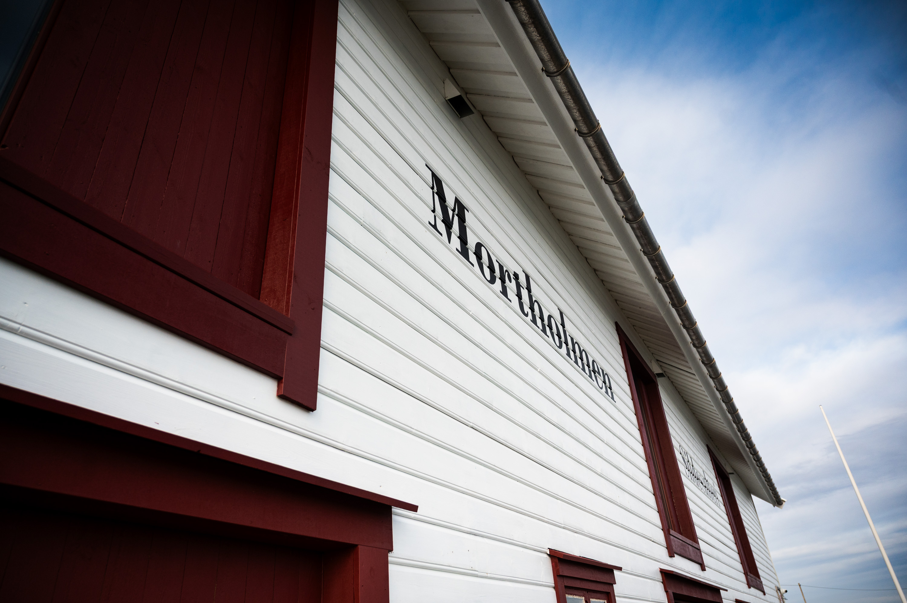 detalj fra hvitmalt fasade med røde vinduer 