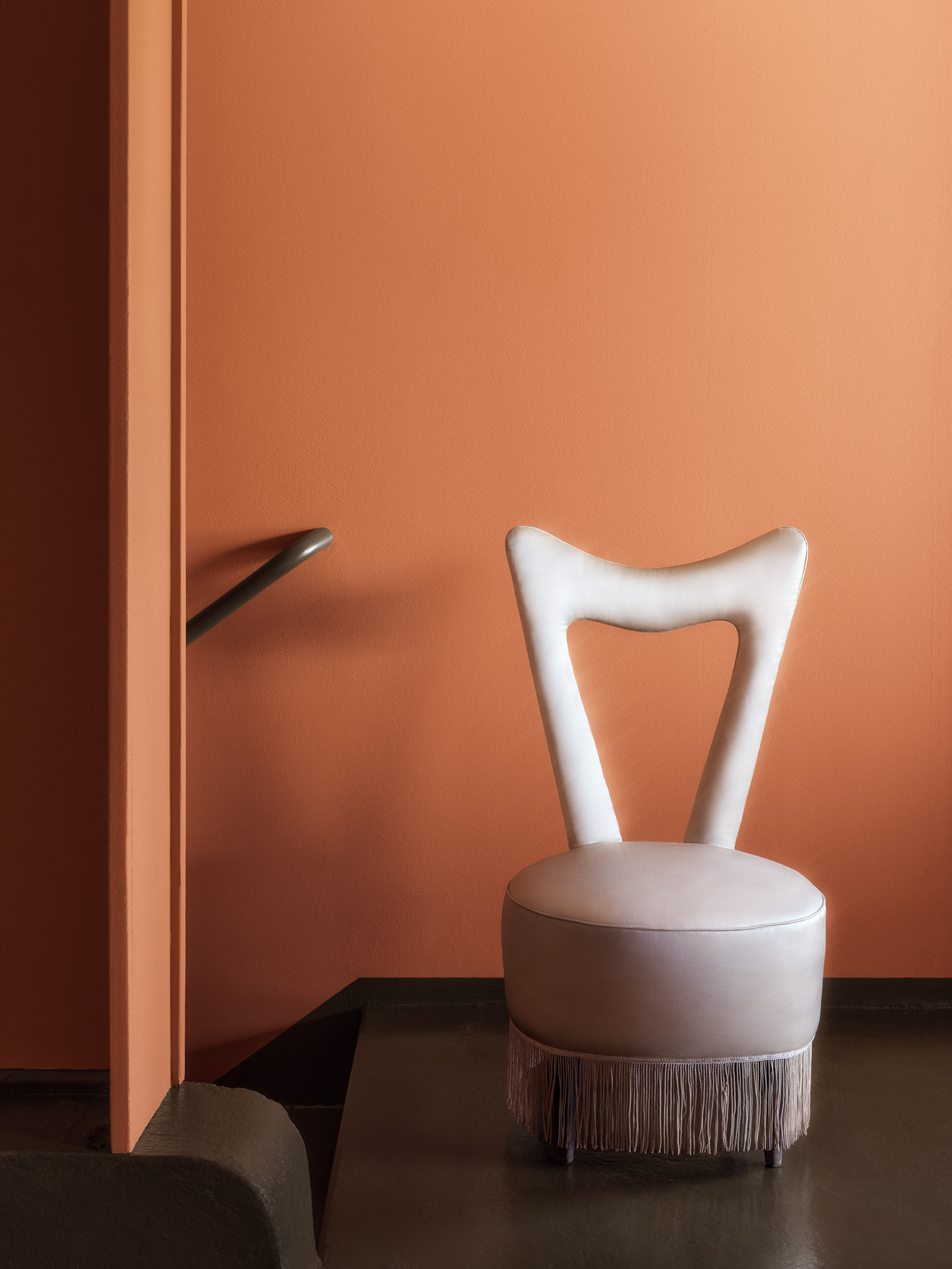 hvit stol mot en terrakottafarget vegg 