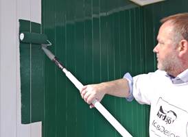 Bruk rull på forlengerskaft for å påføre maling på veggen.