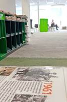 Det grå gulvet brytes opp av grønt ved sentrale plasser. Nedfelte glassplater med trykk forteller avisens og byens historie i en lang korridor midt i lokalet. 
