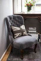 En gammel, hyggelig stol i ny drakt; matt, grå velur, vel tilpasset de øvrige fargene. 