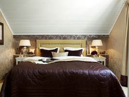 Stor effekt – hvitt tak, tapeter og sengegavl skaper en hyggelig atmosfære i et stilig rom. 
