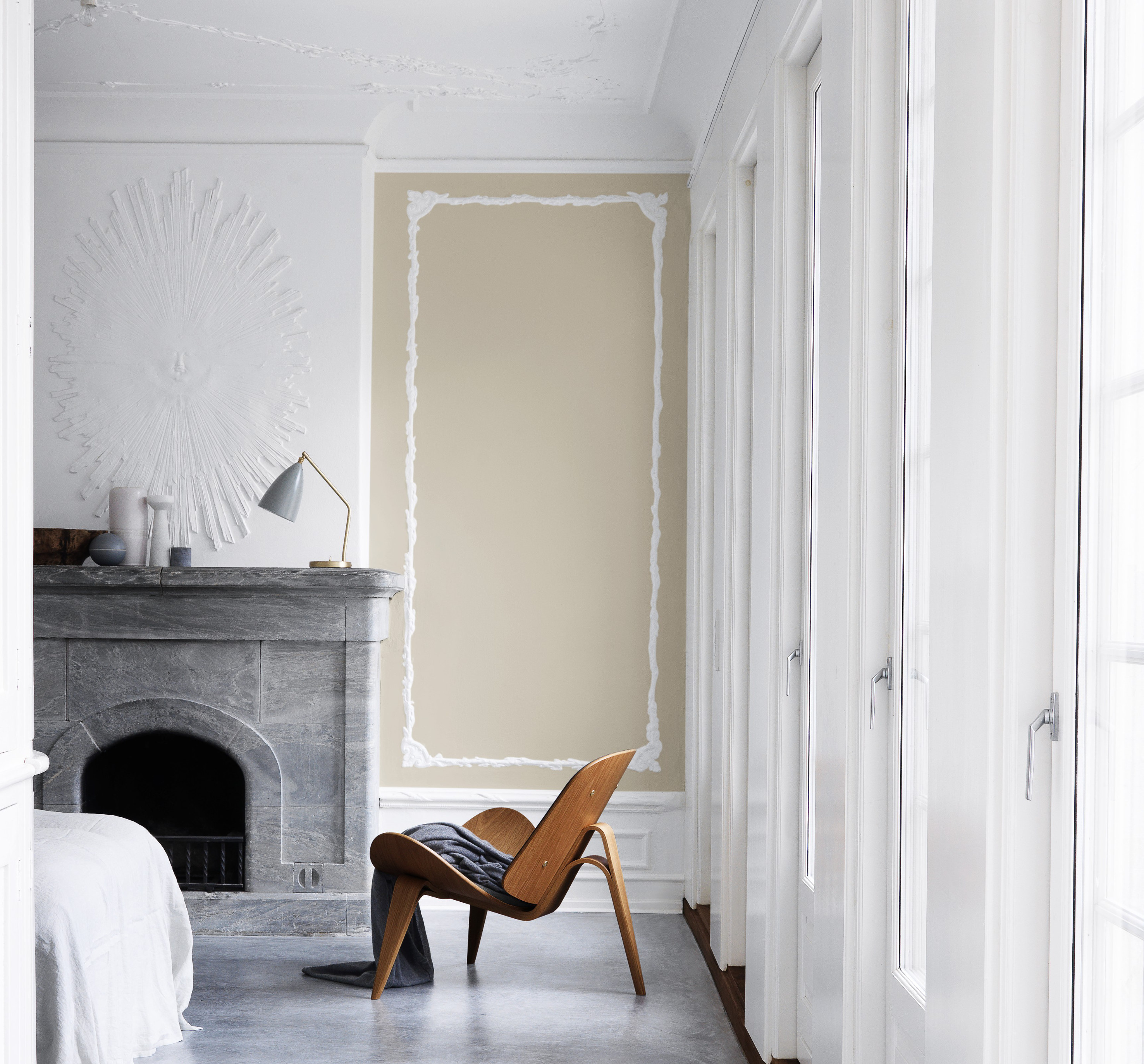 Endeveggen er malt med fargen «Sanddyne», som gir rommet varme. Veggen over peisen, vinduene og taket holder seg strengt til «Råhvit». 