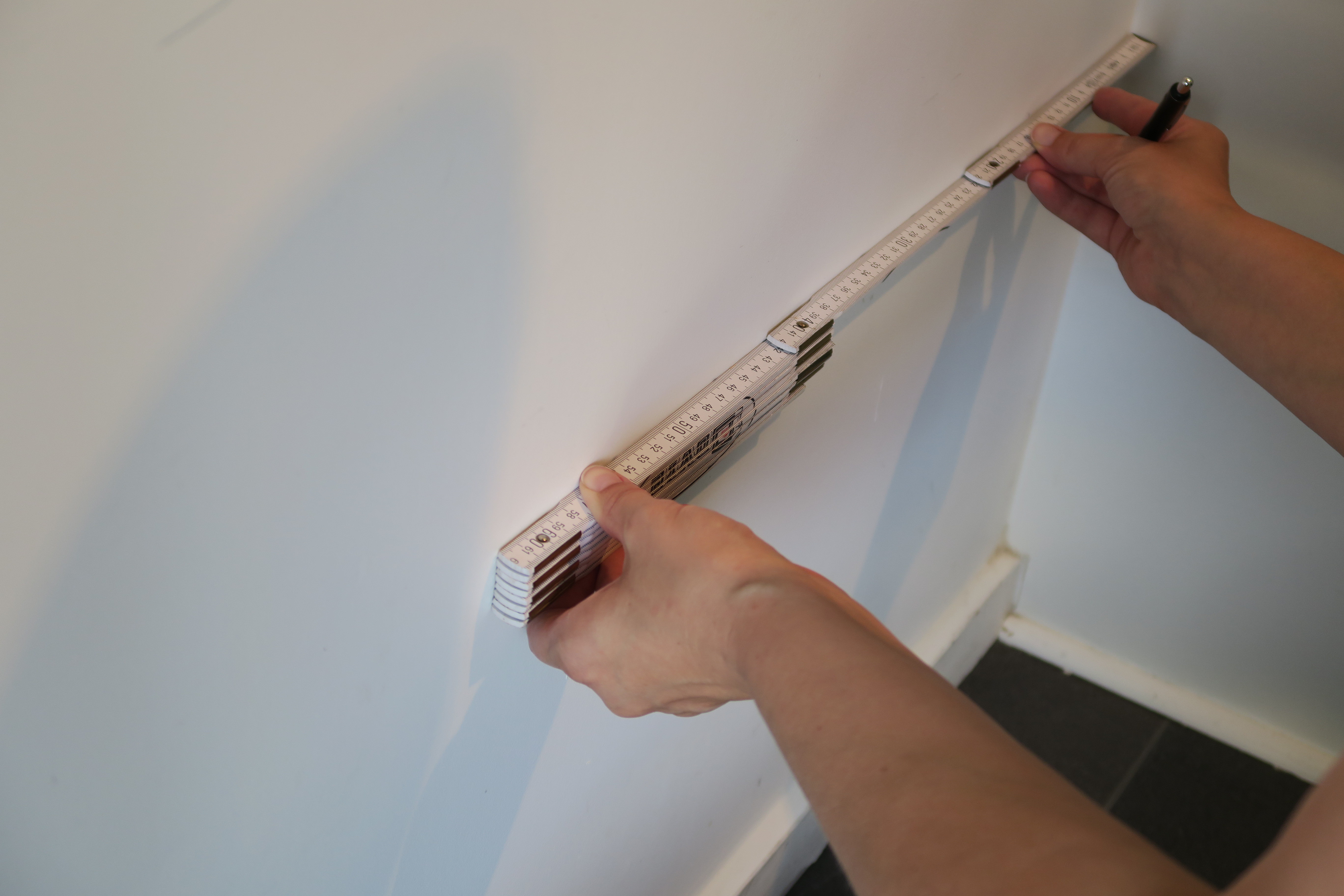 Gummiflisene er 50x50 centimeter. Veggen er 120 centimeter bred. Derfor måler vi opp og fester flisene med rett avstand.