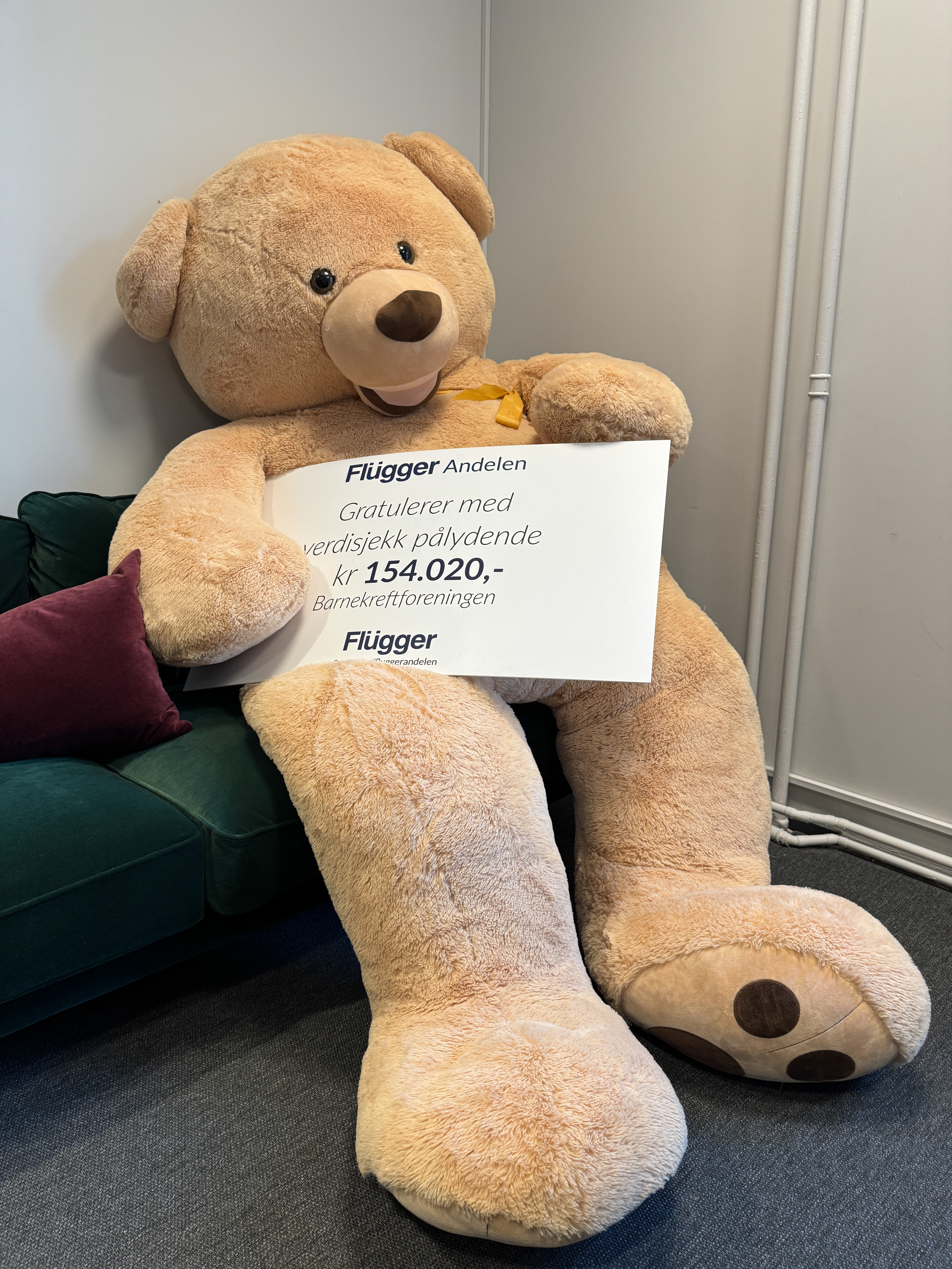 Stor kosebamse holder verdisjekken fra Flügger Andelen til Barnekreftforeningen.