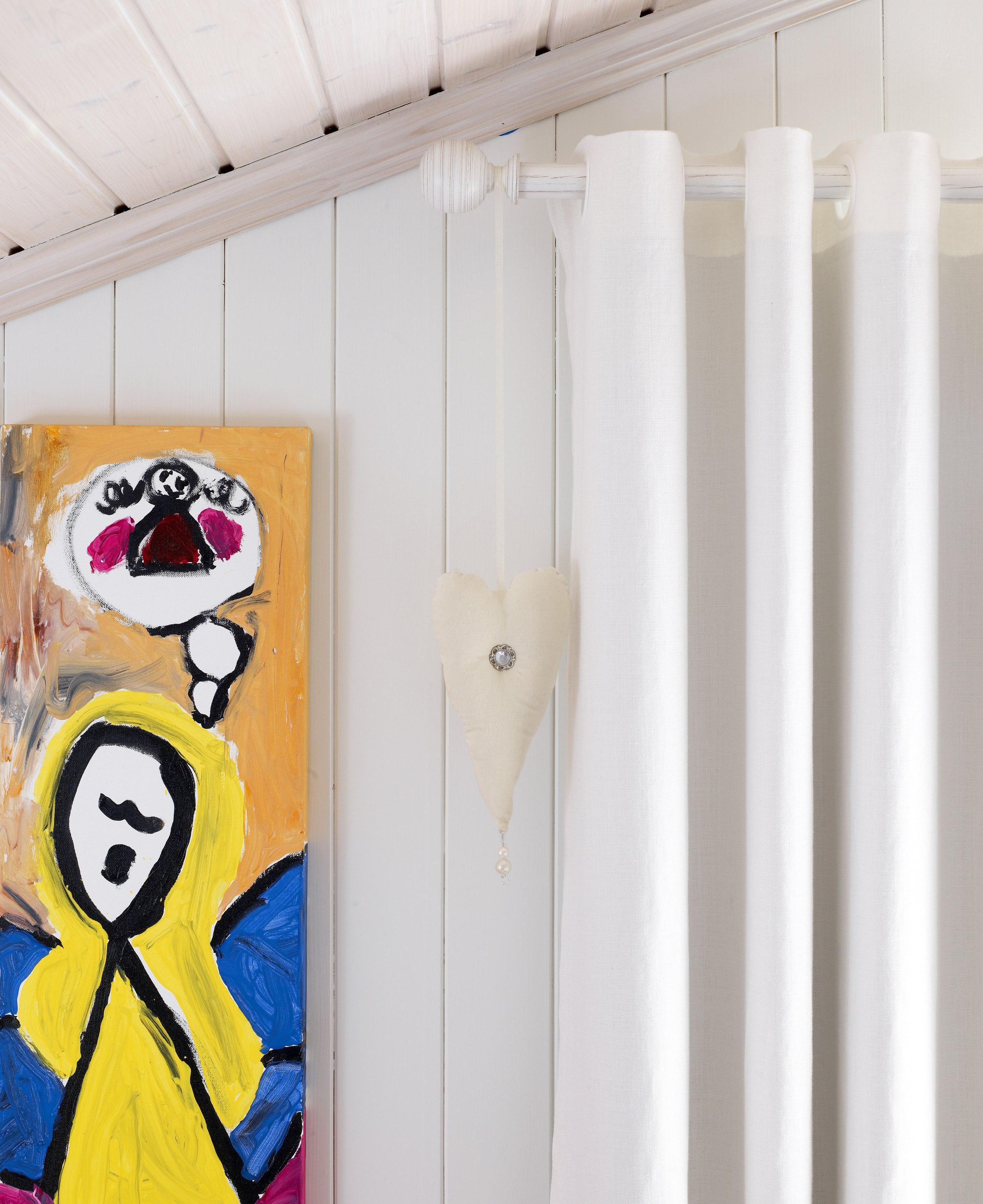 Panellakk møter malte vegger. Lingardinene er hengt opp med maljer. 