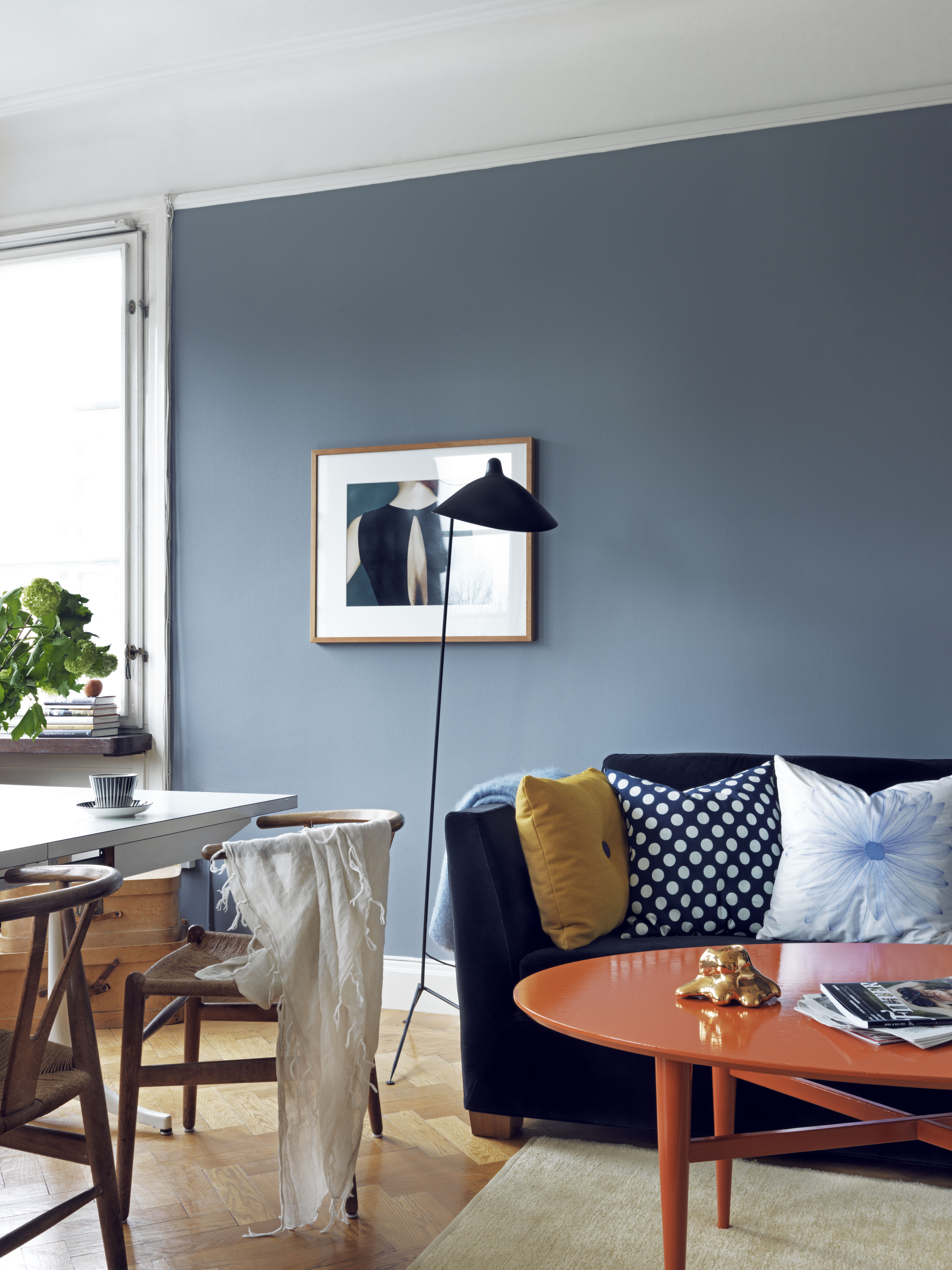 Det oransje bordet og den gule puten står i sterk kontrast til blåtonene, men er med på å gjøre rommet mer interessant.