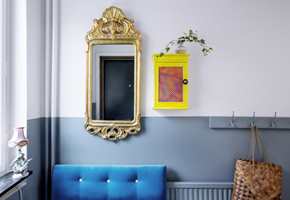<b>SPENNING I DETALJENE:</b> Tofarget vegg gir en fin effekt, uten å virke rotete. Sofaen i kraftig turkis og speilet i gull er viktige stemningsskapere, og nøkkelskapets småfrekke gulfarge er en spennende kontrast til de øvrige fargene. Radiatoren er godt kamuflert i samme farge som veggen. (Foto: Beckers)
