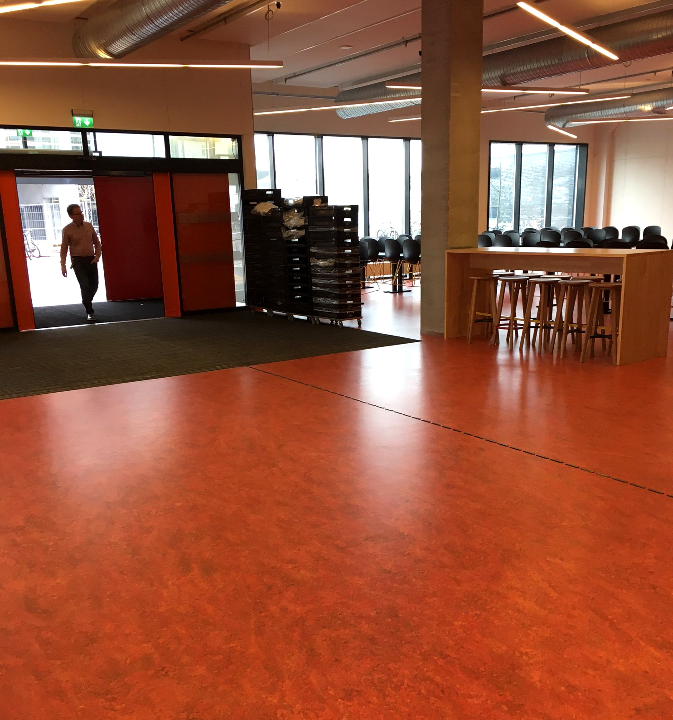 KRAFTFULLT: Kantineområdet har rødt gulv i Marmoleum Vivace, hvor 8 farger er mikset til et spennende fargespill. Her kommer man inn utenfra, så for å sikre at skitt og søle ikke tråkkes ned i linoleumen, er det store avskrapningsmatter innenfor døren.  