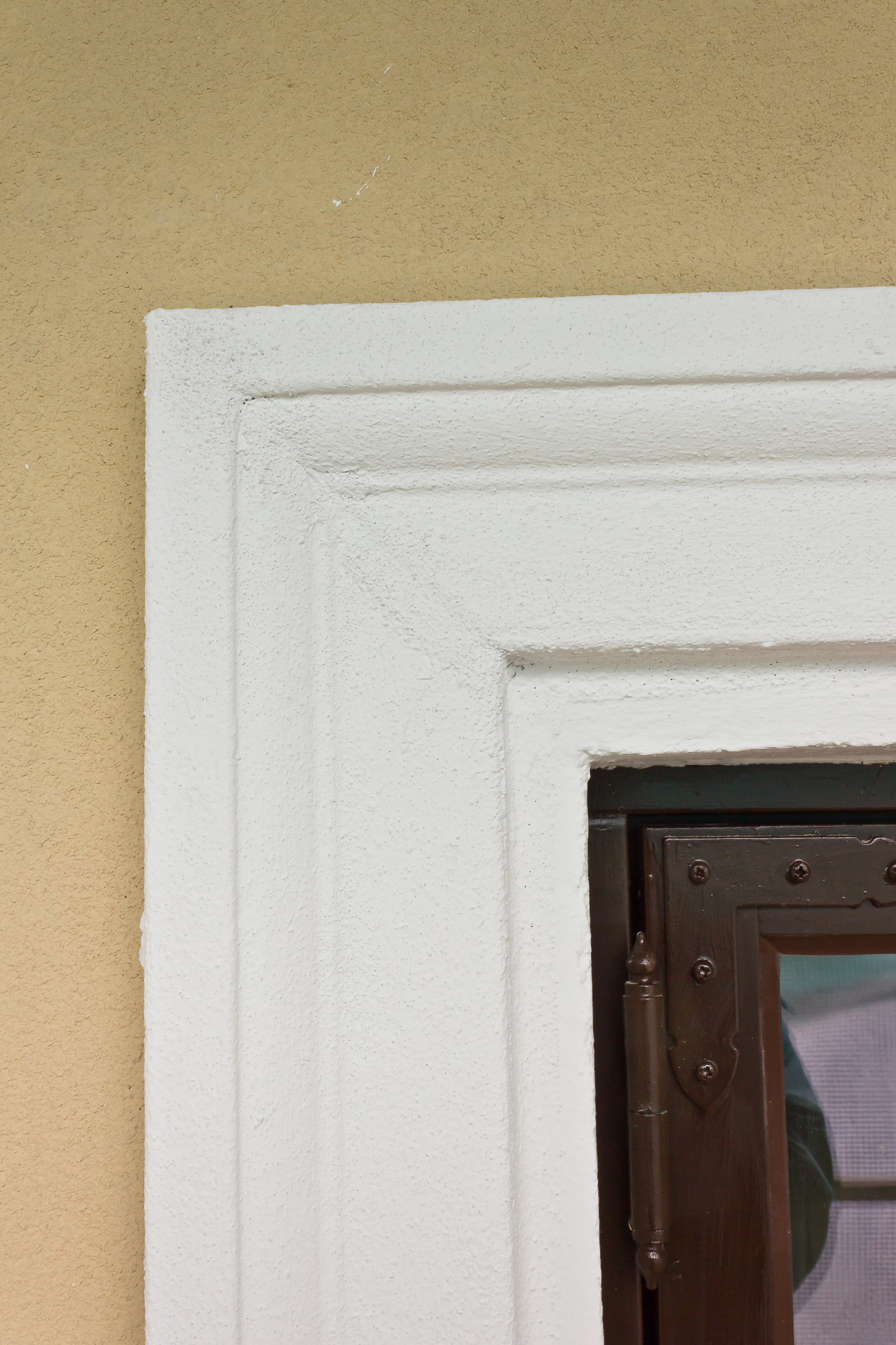 De malte vindusomrammingene ser ut som ekte gipsdekor. Vinduene er av tre, med beslag i gammel stil.