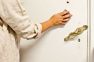 Skap god vedheft til ny maling ved å slipe lett over dørbladet med en finkornet slipekloss eller slipepapir. 