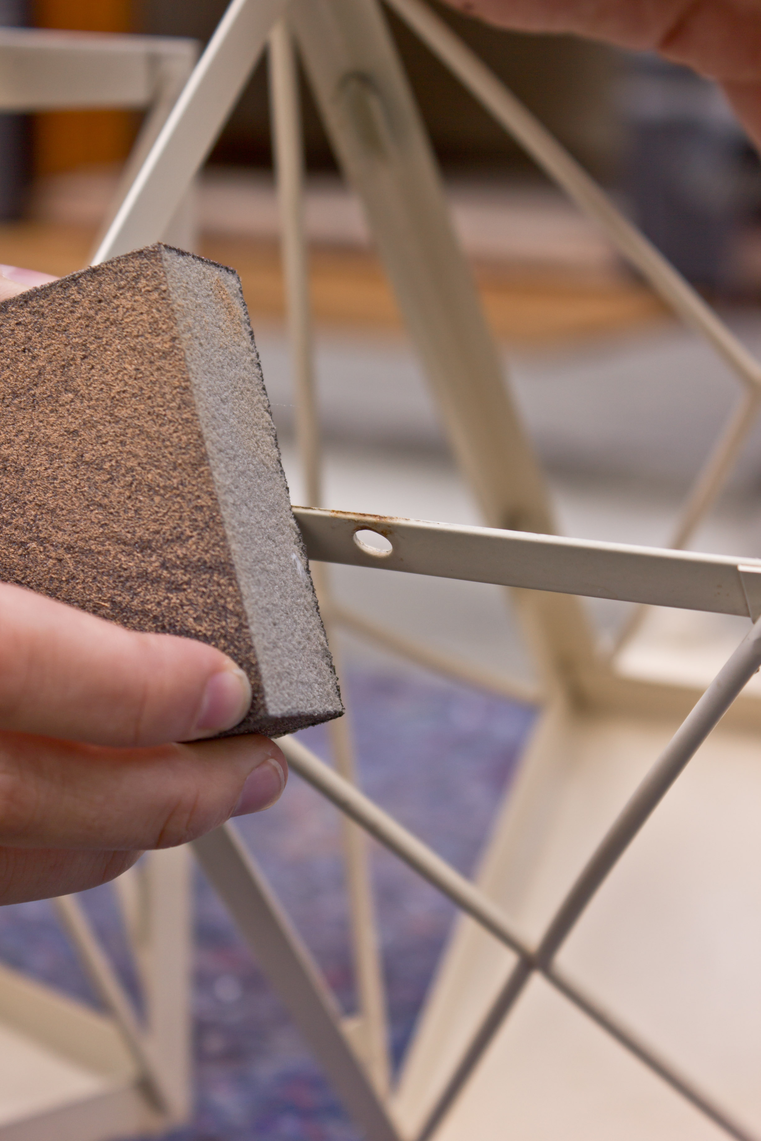 Med slipepad fjerner rust og løs maling fra lyslykt 