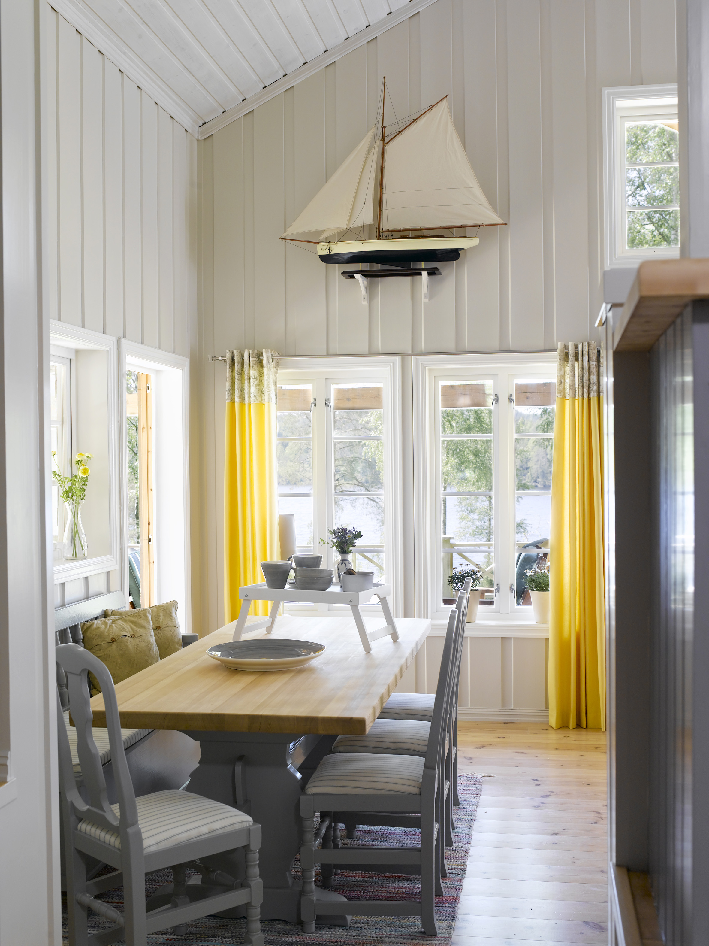 Vinduer og dører på flere kanter gir mye lys til rommet, godt hjulpet av de solgule gardinene. 
