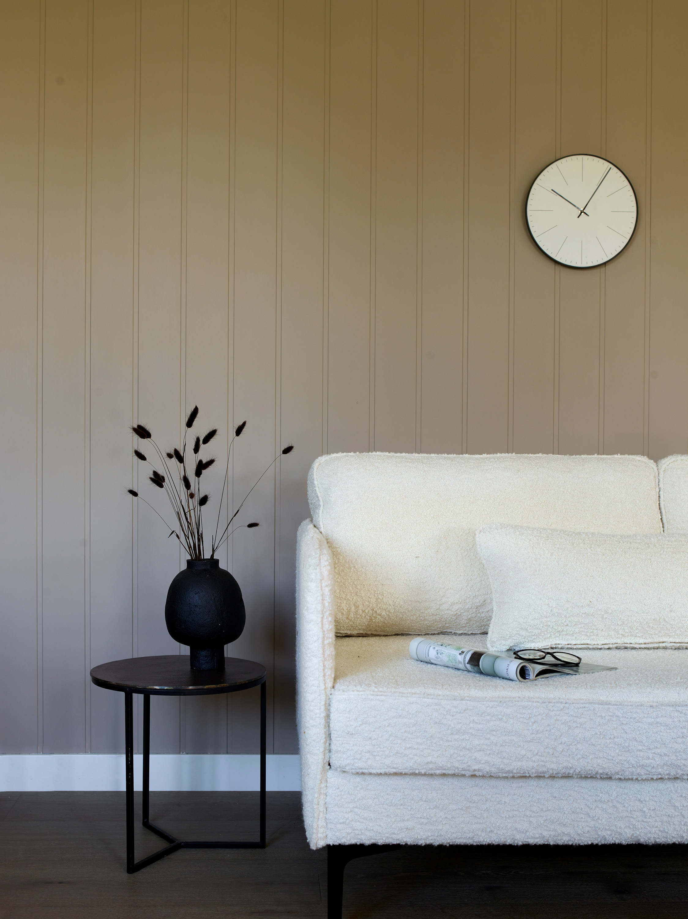 hvit sofa med rundt sort bord mot beige vegg