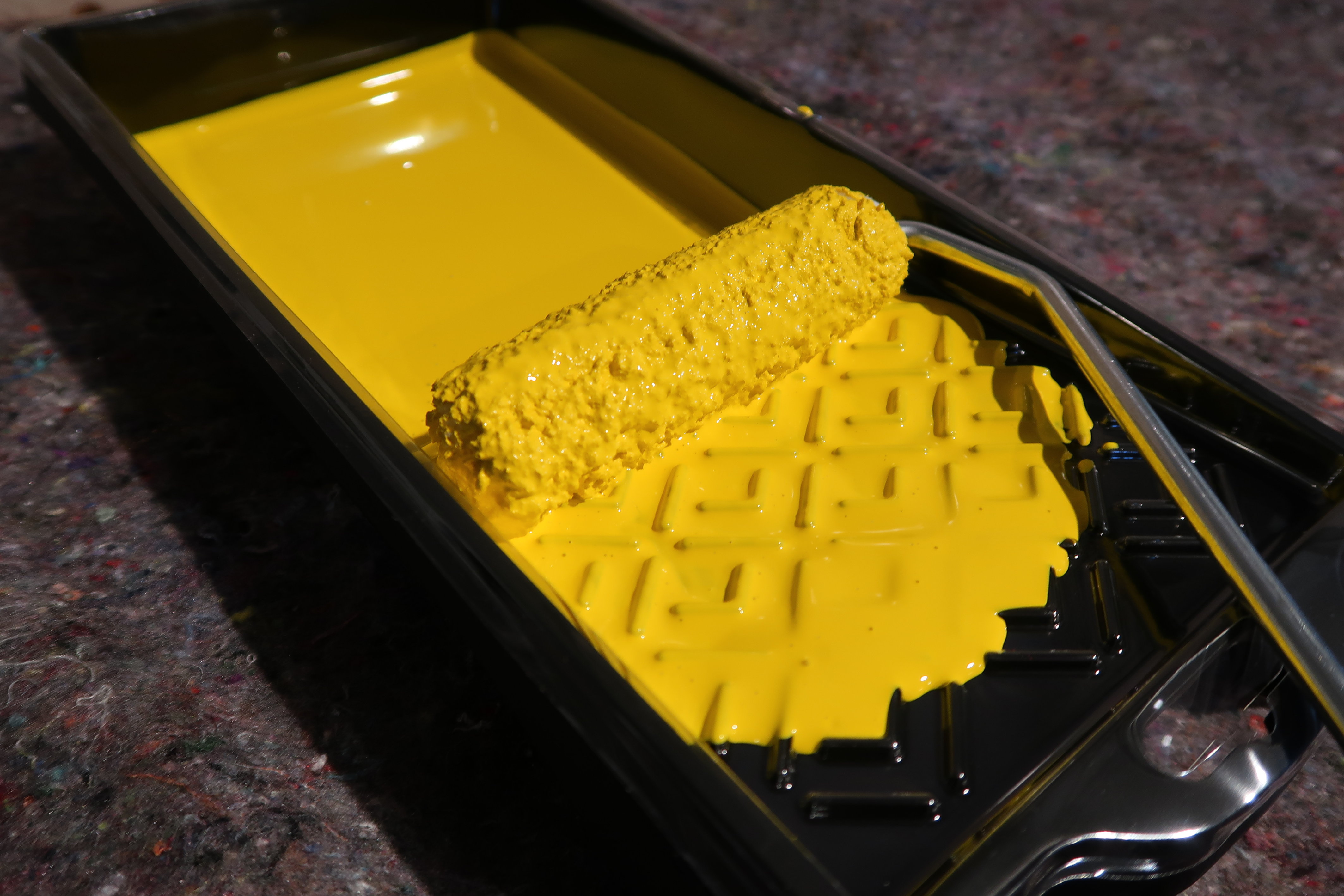 Malerrulle med gul maling i et brett