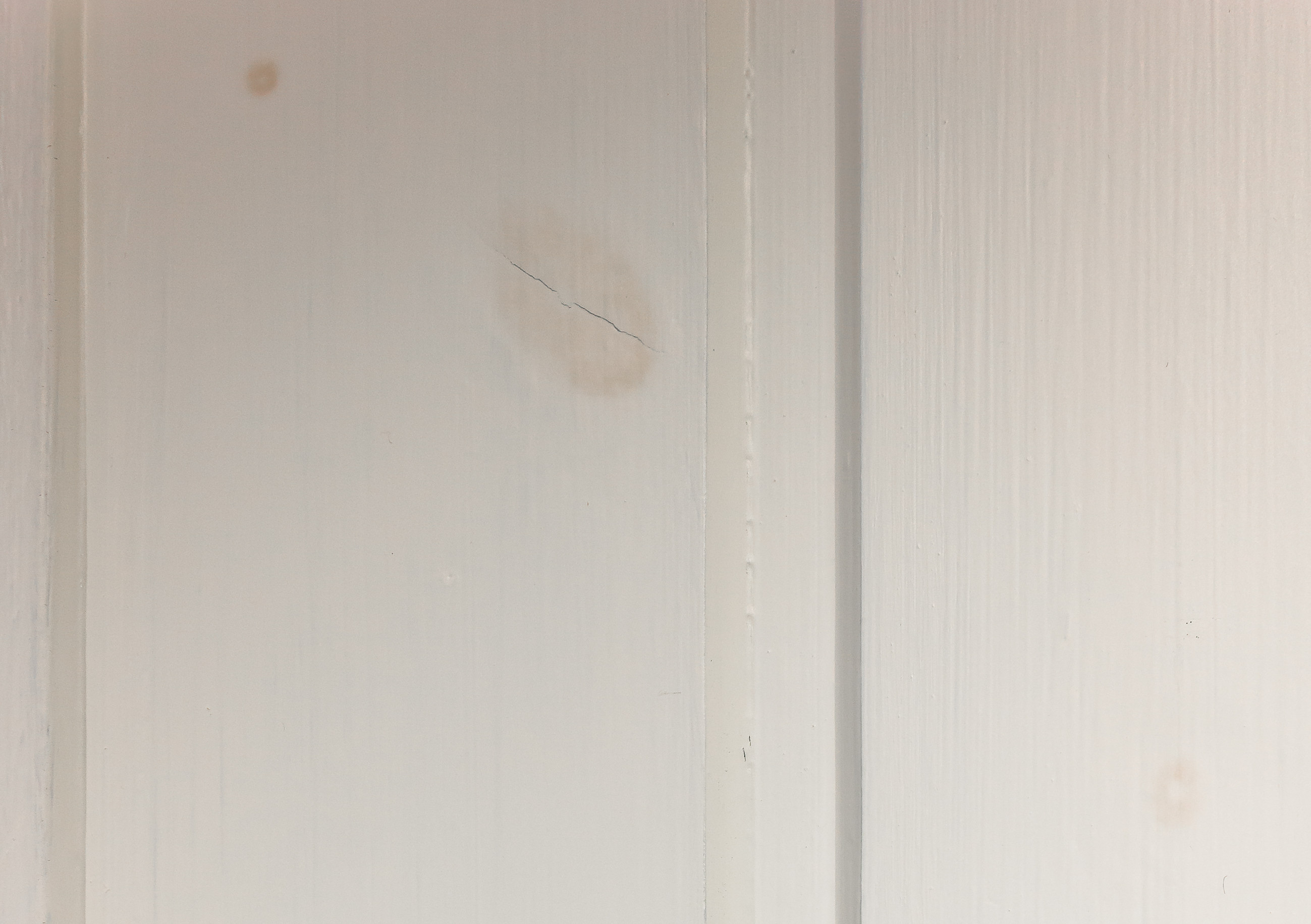 Panel viser gjennomblødning og misfarging fra kvist som synes gjennom malingen.