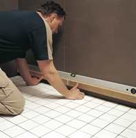 Flislegging på vegg starter ved andre flisrad opp fra gulvet. Fest en rett trelekt til veggen der flisrad nr. 2 skal monteres.