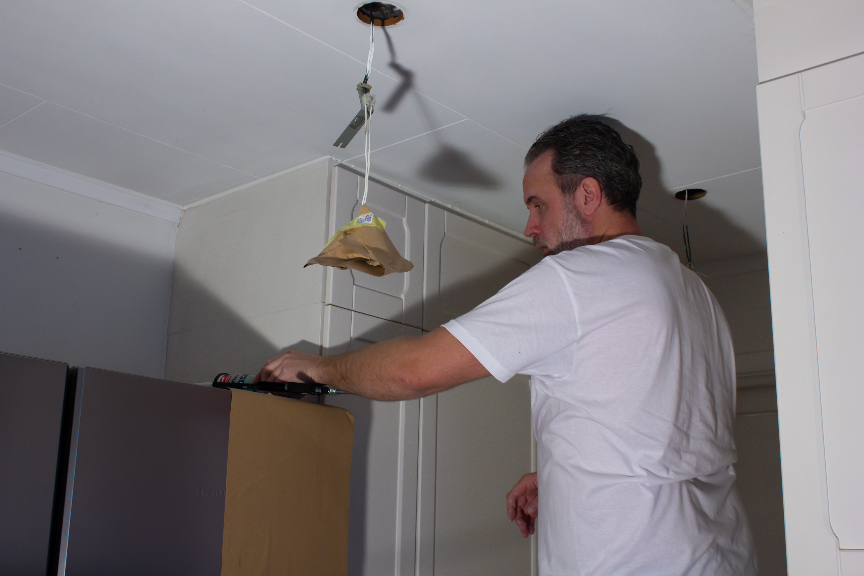 Person fuger lags vegg og taklist.