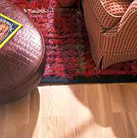 Pallen som er trukket med blankt skinn er en spennende kontrast til de lune og varme overflatene i gulv, teppe, og møbelstoff.