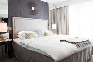 <b>INNBYDENDE HOTELLSTIL:</b> Nordisk luksus preger rommene. Veggene er trukket med vinyltapet som til forveksling ligner silke. Dundyner og puter og sengetøy i hvit og delikat bomull gjør rommet innbydende.