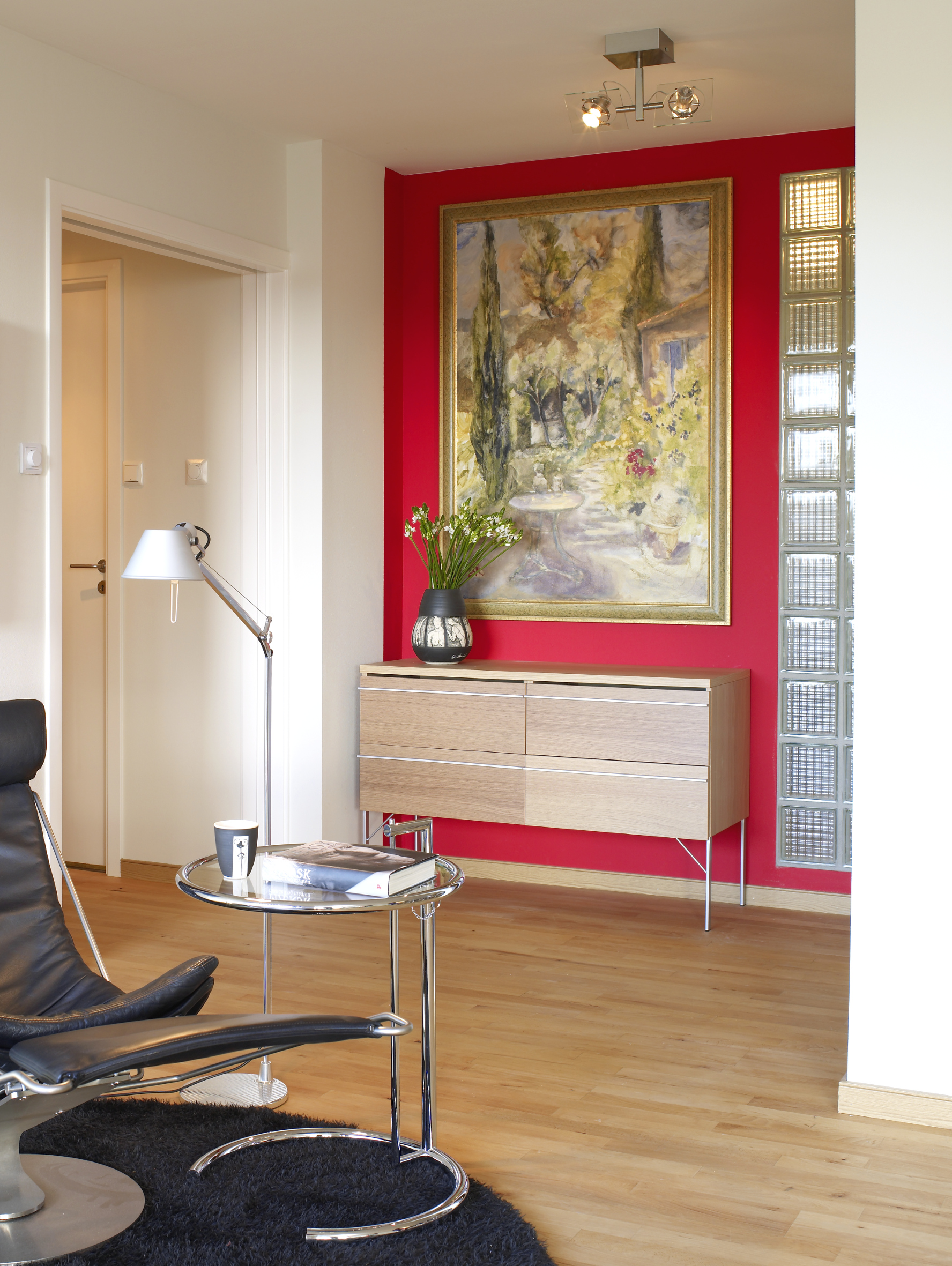 Den heftige rødfargen er kun brukt i nisjen, hvor den fremhever maleriet, skjenken og glassbyggesteinen, og samtidig rammer dem inn. 