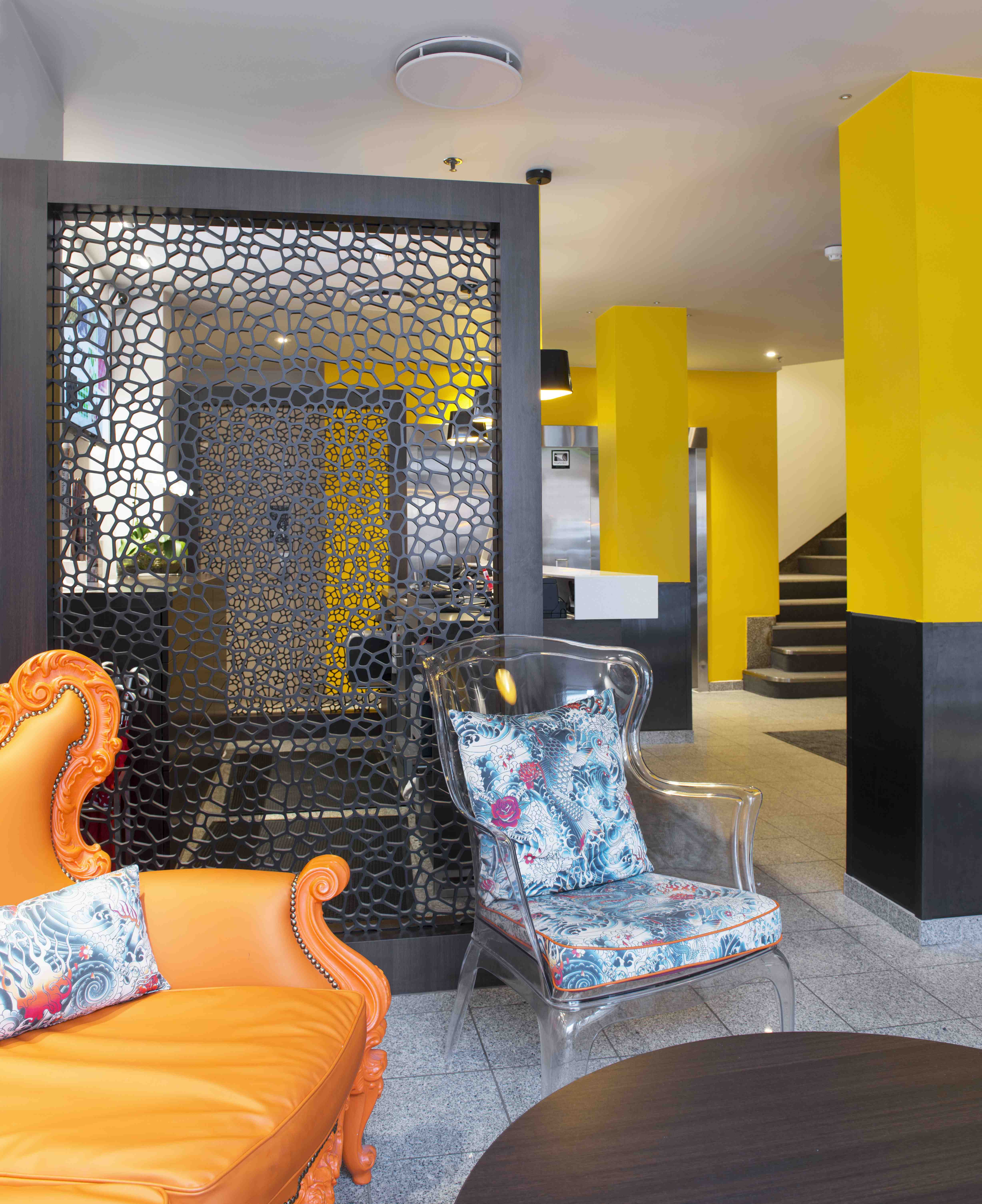 Gulmalte søyler, laserskårede skillevegger, oransje møbler og puter i et frekt stoff fra Jean-Paul Gaultier er noen av de mange fargene og materialene i resepsjonen. 