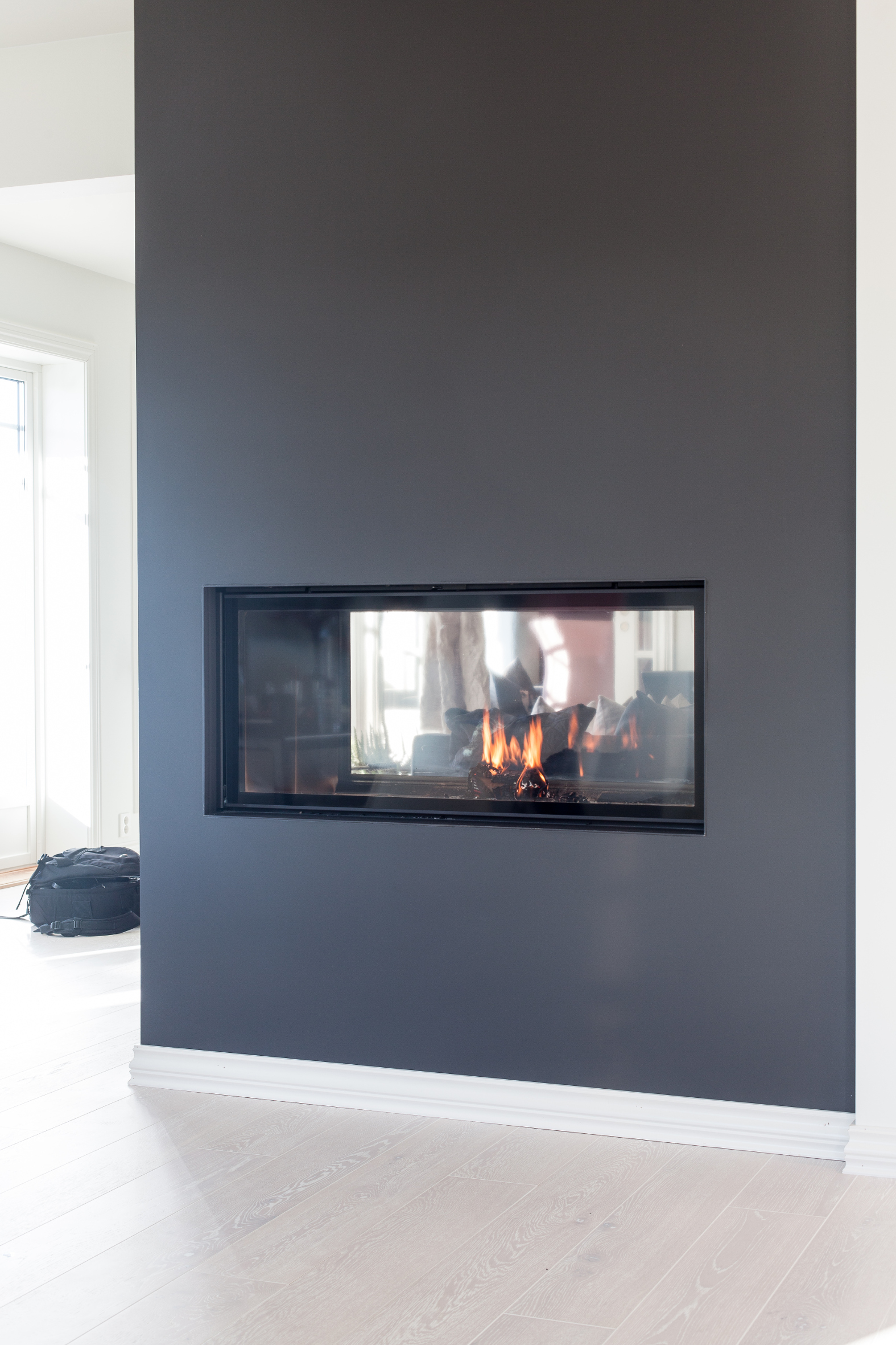 FREMHEVET Peisen er synlig fra begge sider av rommet, og matt kalkmaling i en m&oslash;rk gr&aring;farge gir den et elegant preg. Her er den en viktig, synlig del av interi&oslash;ret, til forskjell fra om den var hvitmalt.