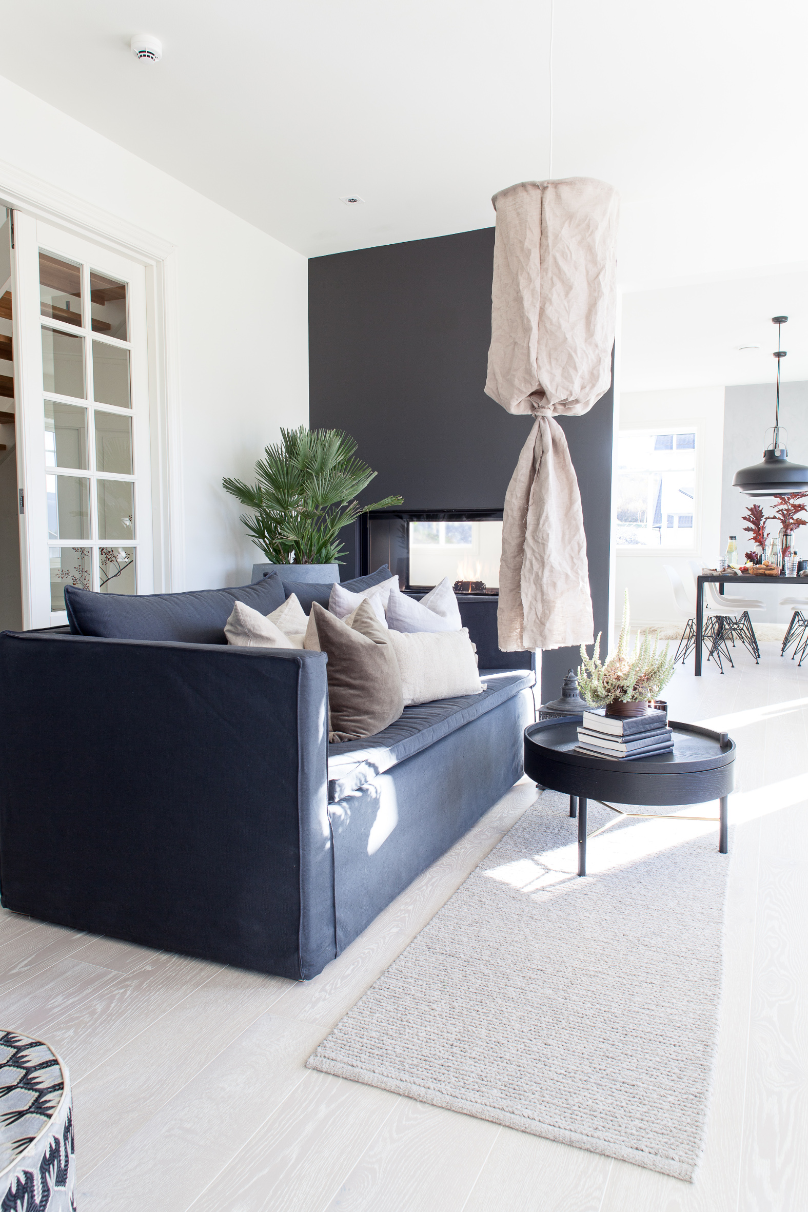 M&Oslash;RKT SKILLE M&oslash;rke elementer mot lyse vegger. Peisen avgrenser stuen fra kj&oslash;kken og spisestue, som er holdt i lysere farger.