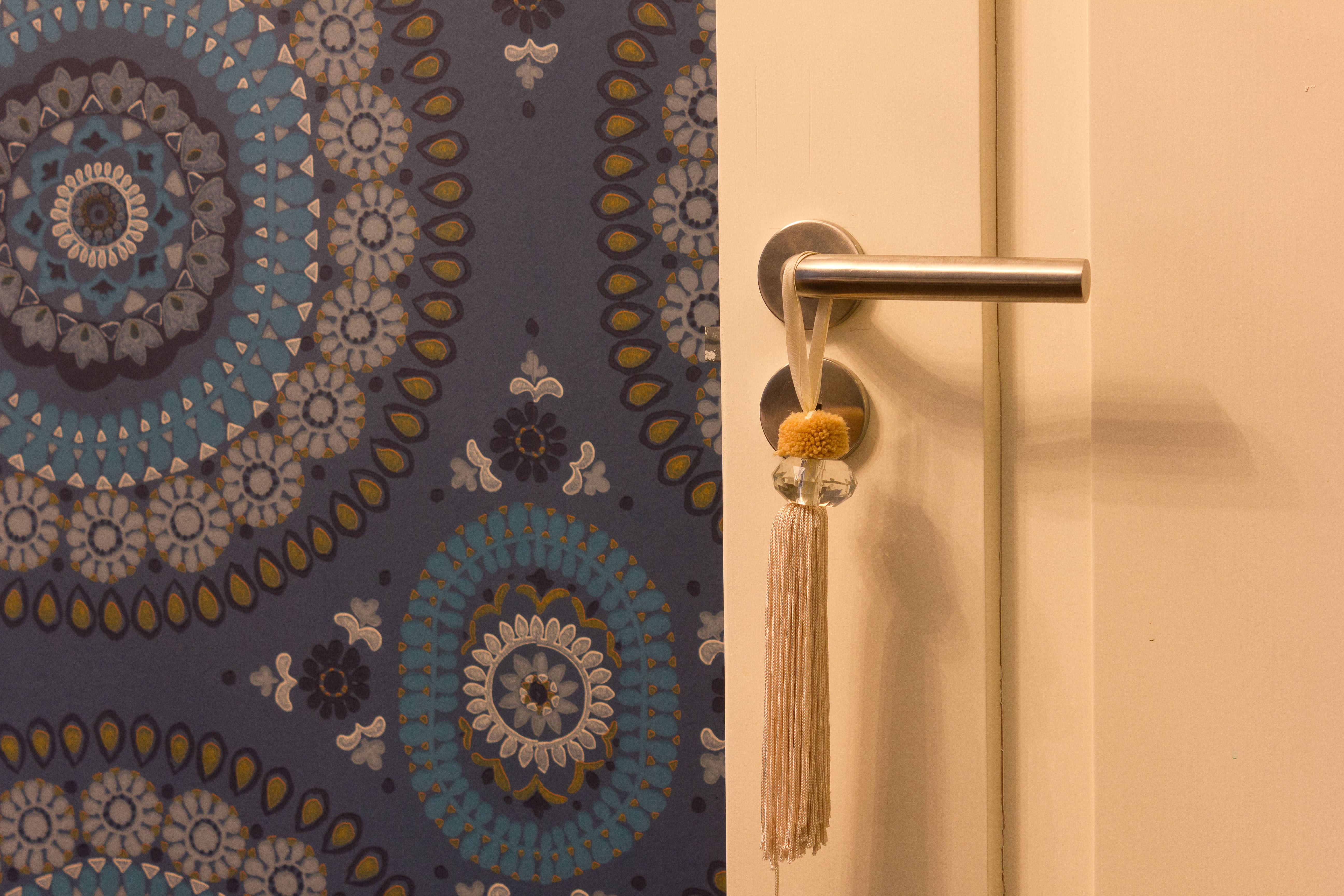 Soverommet er alt annet enn minimalistisk. Tapet med stort rosettmønster pryder alle fire veggene og vinduene er omrammet av lange forede gardiner som skjermer mot innsyn, lys og støy. 