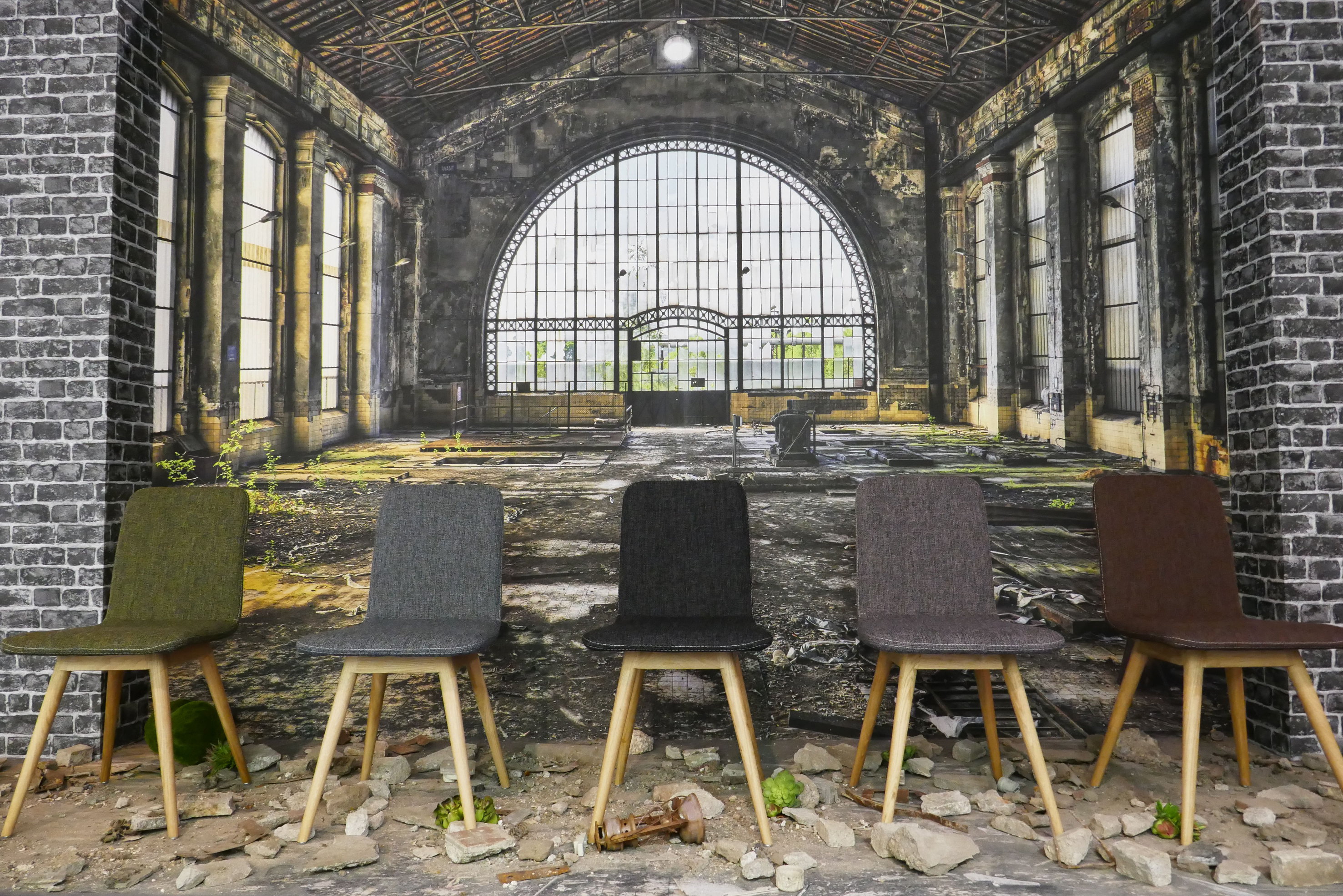 KONTRASTER: Men like fullt harmonisk. Enkle stoler i dempede naturfarger, myke tekstiler og lyst treverk mot en rå industrihall (fototapet). (Foto: Bjørg Owren/ifi.no)