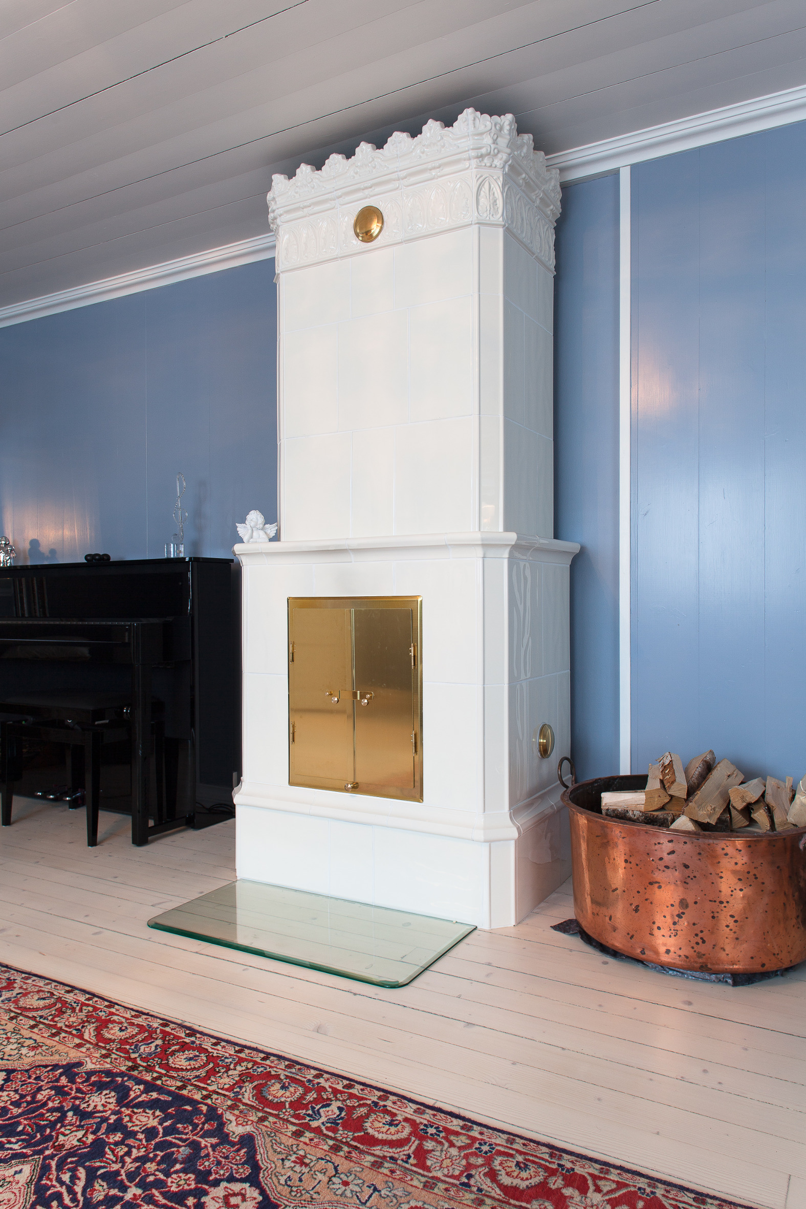 Kakkelovnen står i stram og staselig giv akt i den blå stuen, vakker mot den blå veggen. 