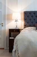 Sengen rammes inn av sengegavlen og nattbordene, en fin effekt i det store, lyse rommet. 