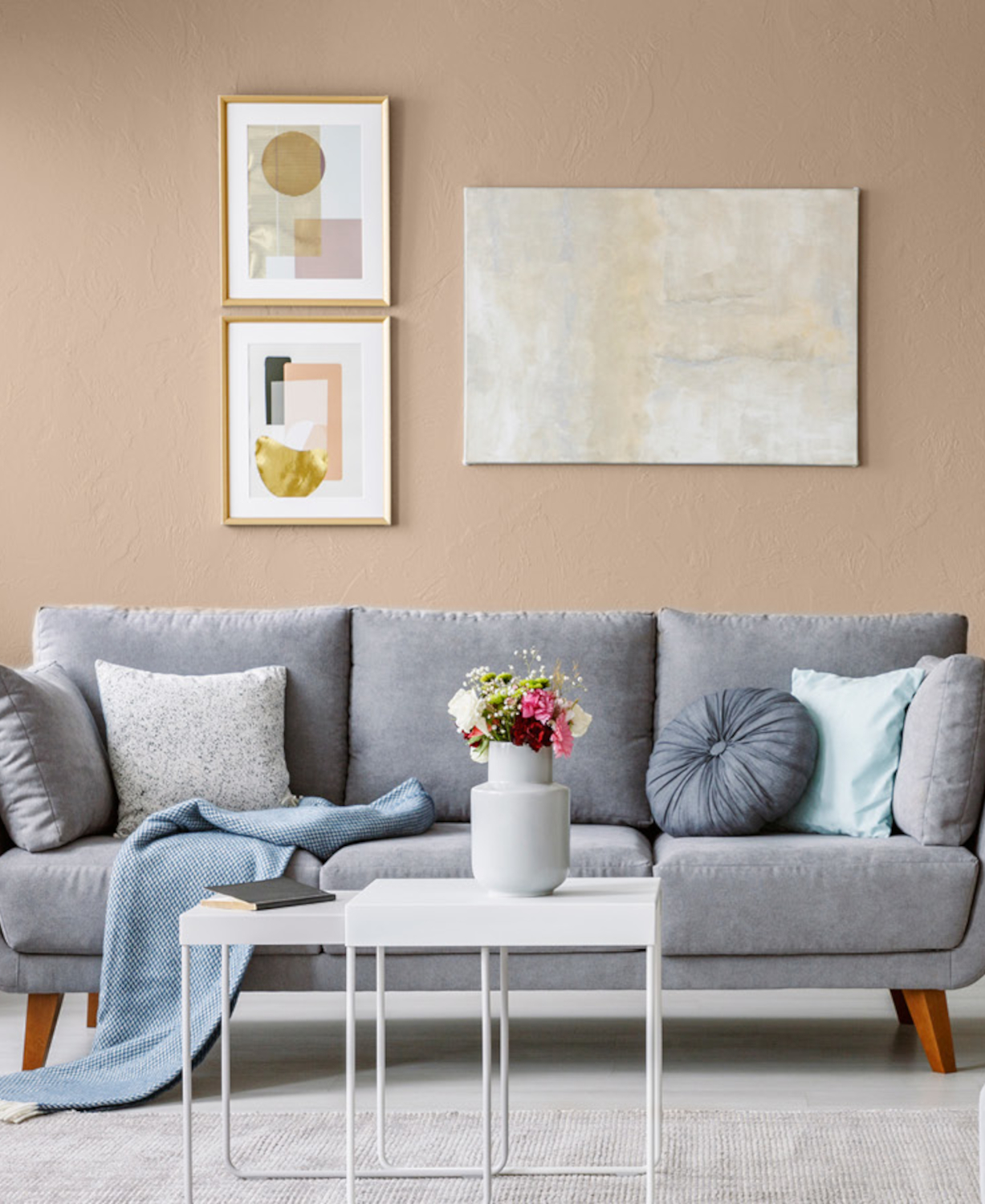 grå sofa foran vegg i beige som trekker mot rødt