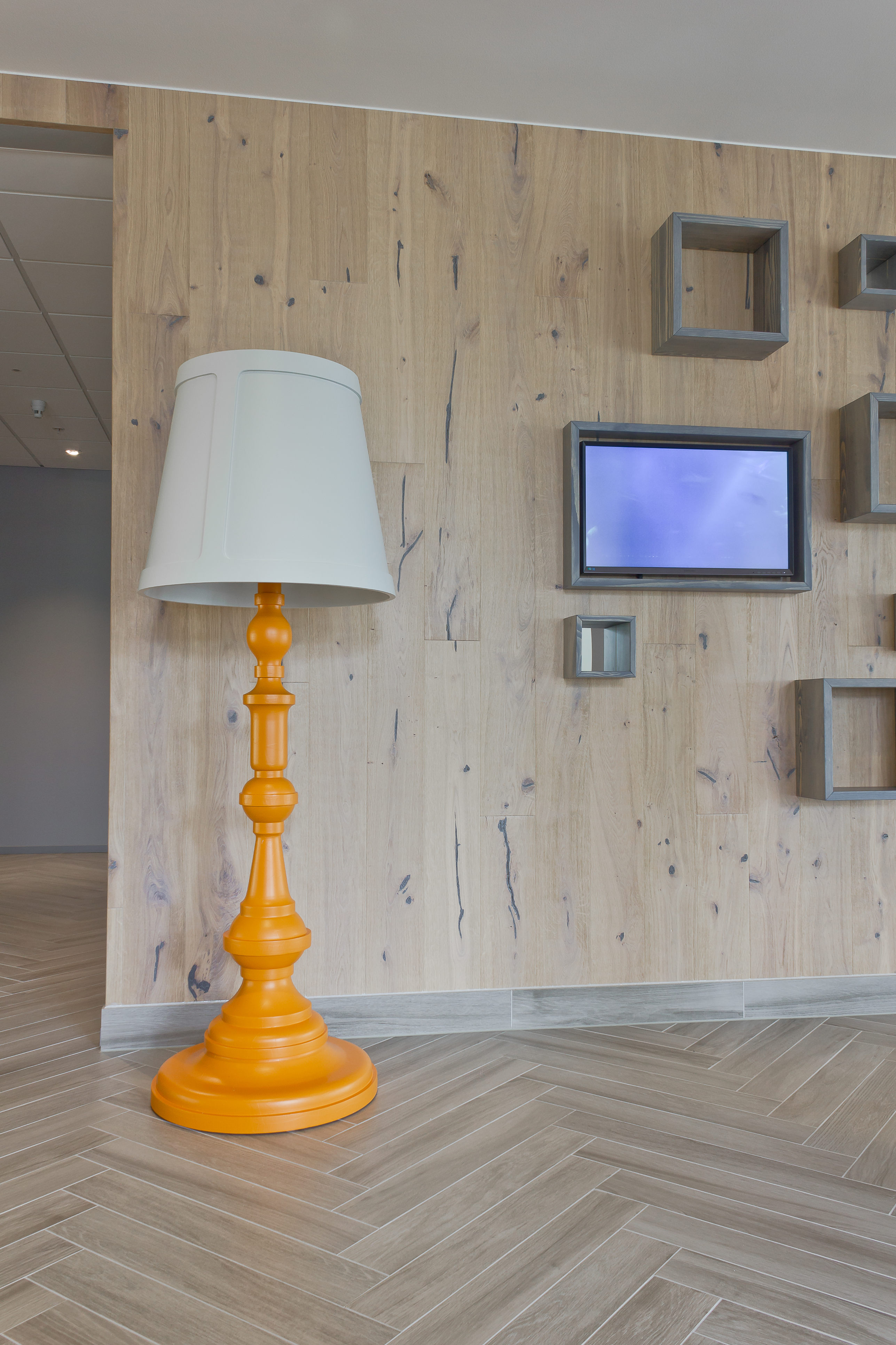 Svære lamper med dreid trefot bidrar til lekenheten i interiøret, og det gråpigmenterte treverket gir et værbitt preg som trekker sjøen inn.