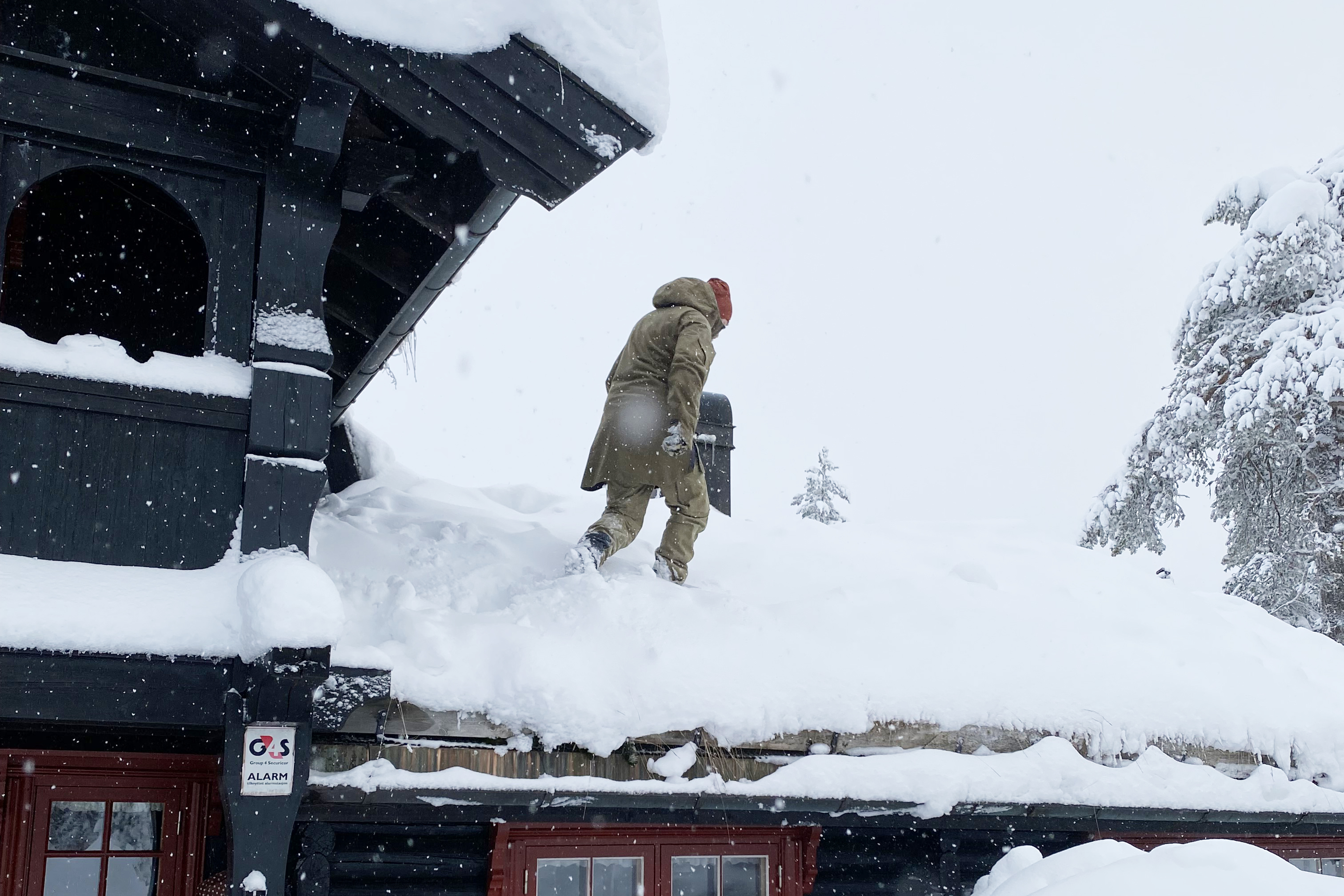 Person som måker snø av hyttetaket