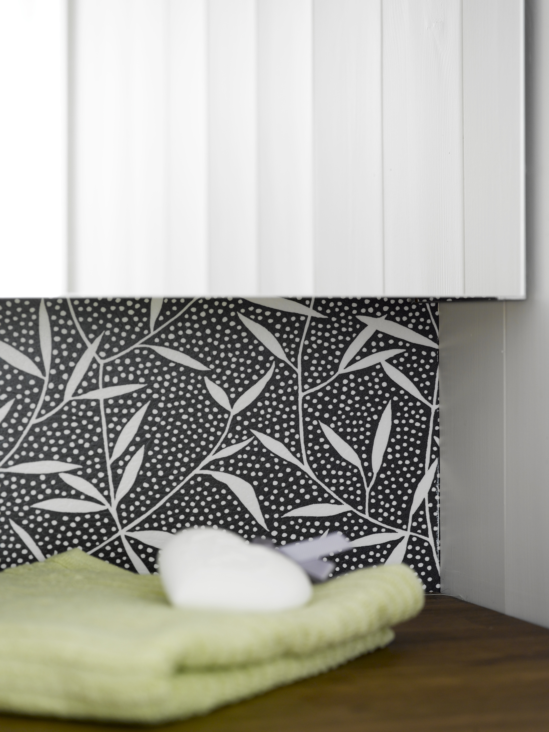 Mønsteret på våtromsvinylen gir rommet karakter, i fin kontrast til det hvitmalte panelet. 