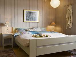 Upraktiske kommoder vek plassen for nette nattbord, som er malt i en lys, varm gråfarge, mens sengen er holdt i dus grønn.  