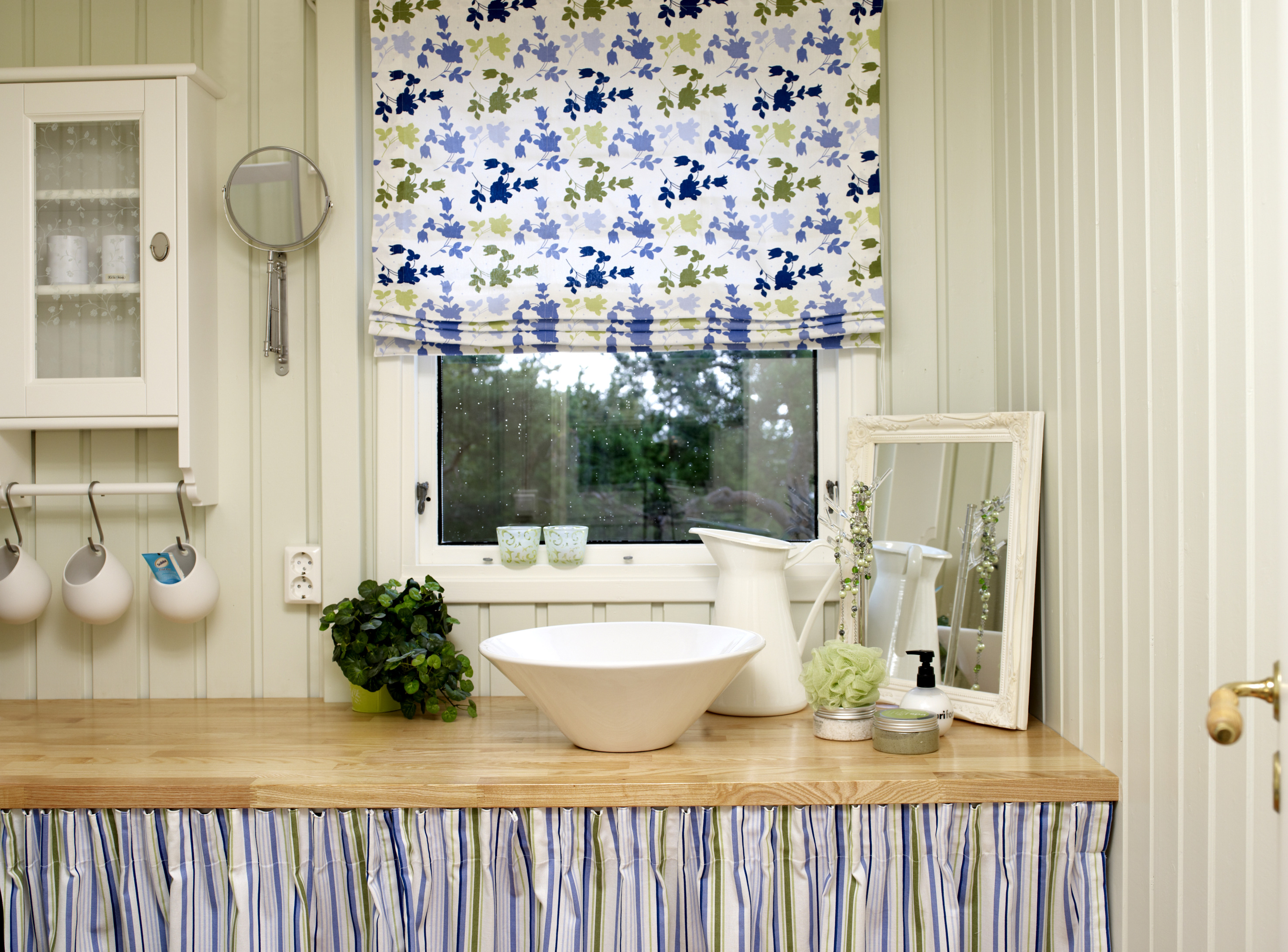 Benken og forhenget skjuler hyller med nødvendige ting & tang. Gardin og forheng har samme farger, som gjør at blomstene og stripene fungerer så bra sammen. 