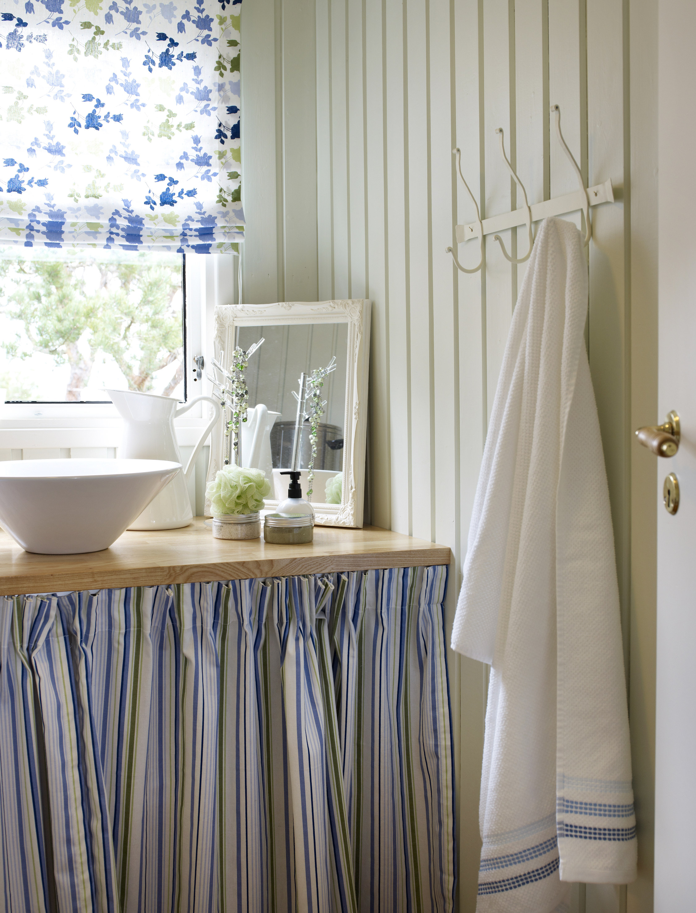 Den duse grønnfargen danner en nydelig bakgrunn for umalt treverk, tekstiler med farger og innslagene av hvite elementer. 