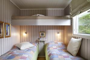 Fresht, hvitmalt tak og varmbeige vegger utgjør et hyggelig soverom. De tre køyene er praktisk plassert i forhold til hverandre, og skaper luft. 