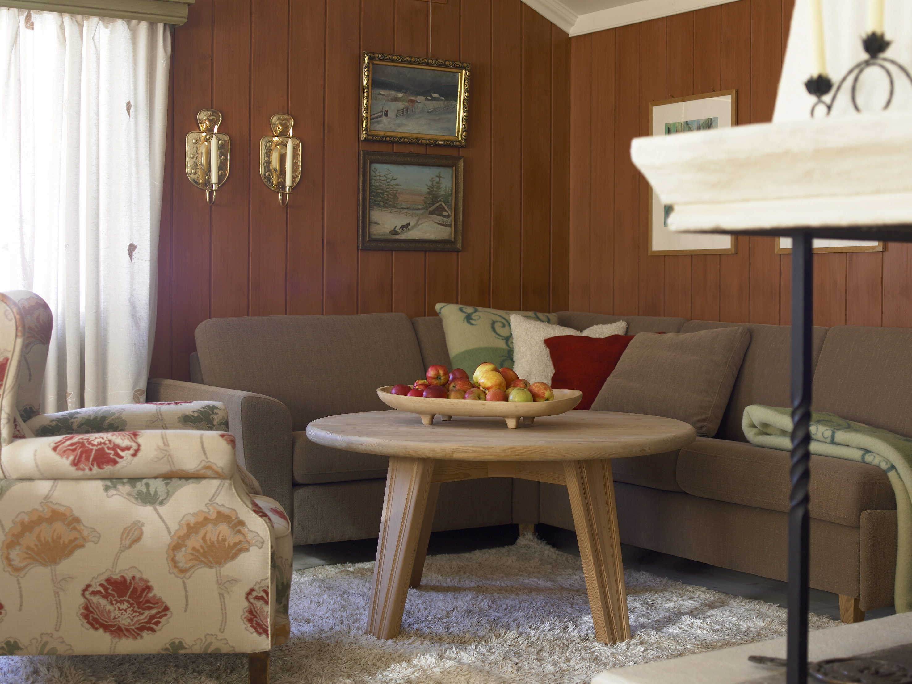 Gode jordfarger. En varm, dempet veggfarge med patinert overflate, gråbeige sofa, naturfargede gardiner og teppe og lenestol med nytt trekk. 