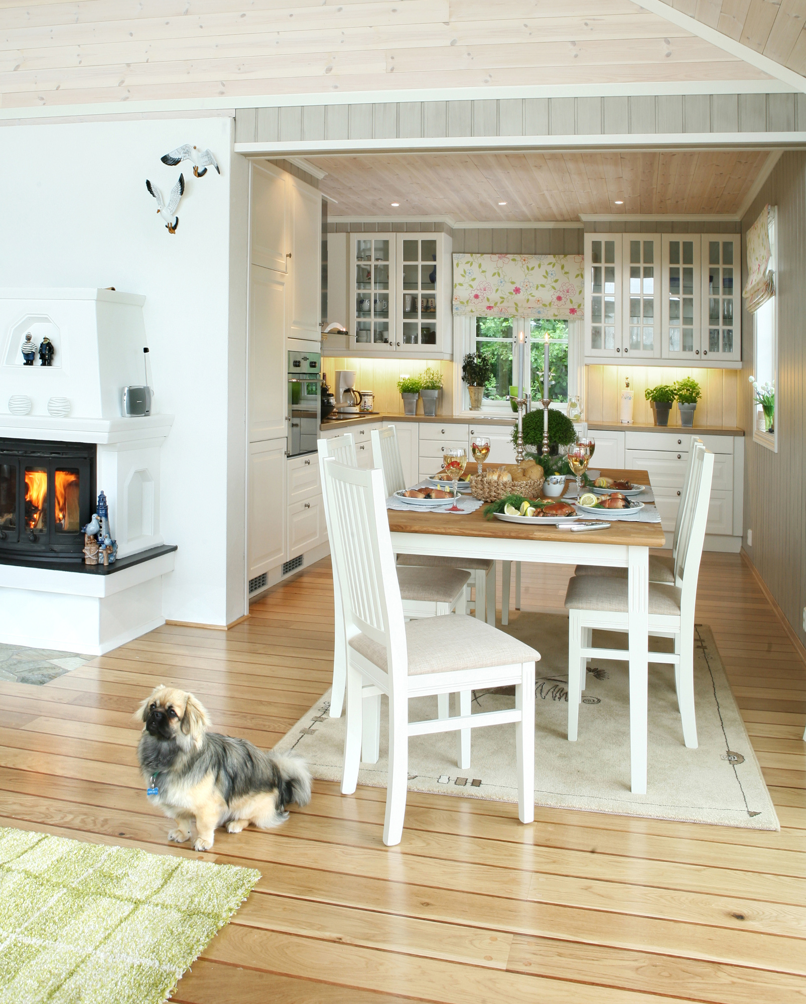 Åpen løsning mellom kjøkken og stue skaper verdifull kontakt mellom både rom og mennesker. Kjøkkennisjen er lys og romslig, med plass til store og små mens maten tilberedes. Og knitringen fra peisen har man glede av både i sofaen og til bords.  