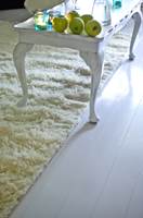 Furugulvet ble malt i en lys grå farge. Det hvite flossteppet gir stua et eksklusivt preg og luner under bena.