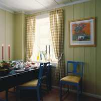 Til veggpanelet på kjøkkenet ble det valgt en gulhvit farge som nok kan ha et grønnskjær i noen lysforhold. Den skaper lunhet, er en god kontrast til den blå innredningen og henter opp toner fra den gule midtstuen og inngangspartiet.