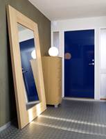 Inngangsdøren er en krafig fargeflekk i blått. Fondveggen med speilet synes fra stuen, og har fått en overflate og farge lik betongen huset er bygd av.