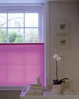 Den rosa varianten er en rullgardin festet i bunnen av vinduskarmen som betjenes med kjedetrekk. Gardinen kan da skjerme akkurat den delen av vinduet som er nødvendig. Lages etter mål.